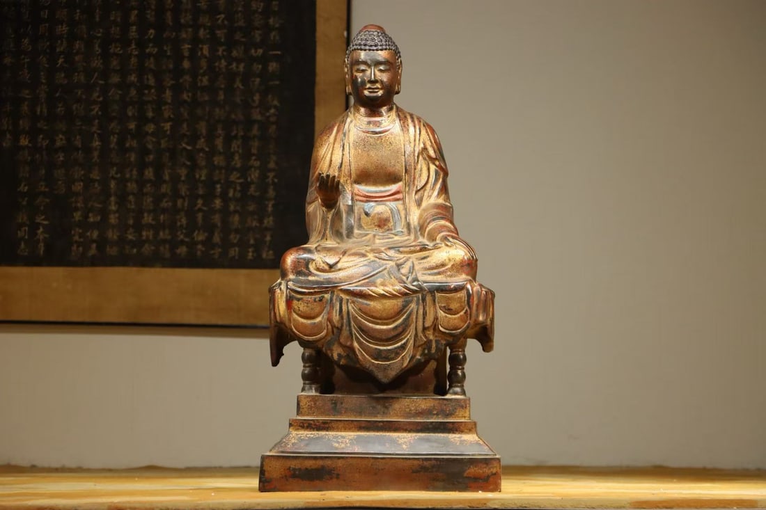 A BRONZE LACQUER GOLD STATUE OF SAKYAMUNI SITTING BUDDHA FROM THE MING DYNASTY: Height:85cm(33.46in) Width:42cm(16.54in) Weight:38000g(83.77lb)Lacquered gilt bronze seated statue of Sakyamuni Buddha. The bronze body is fully coated with lacquer and gilded. The Buddha has spiral h