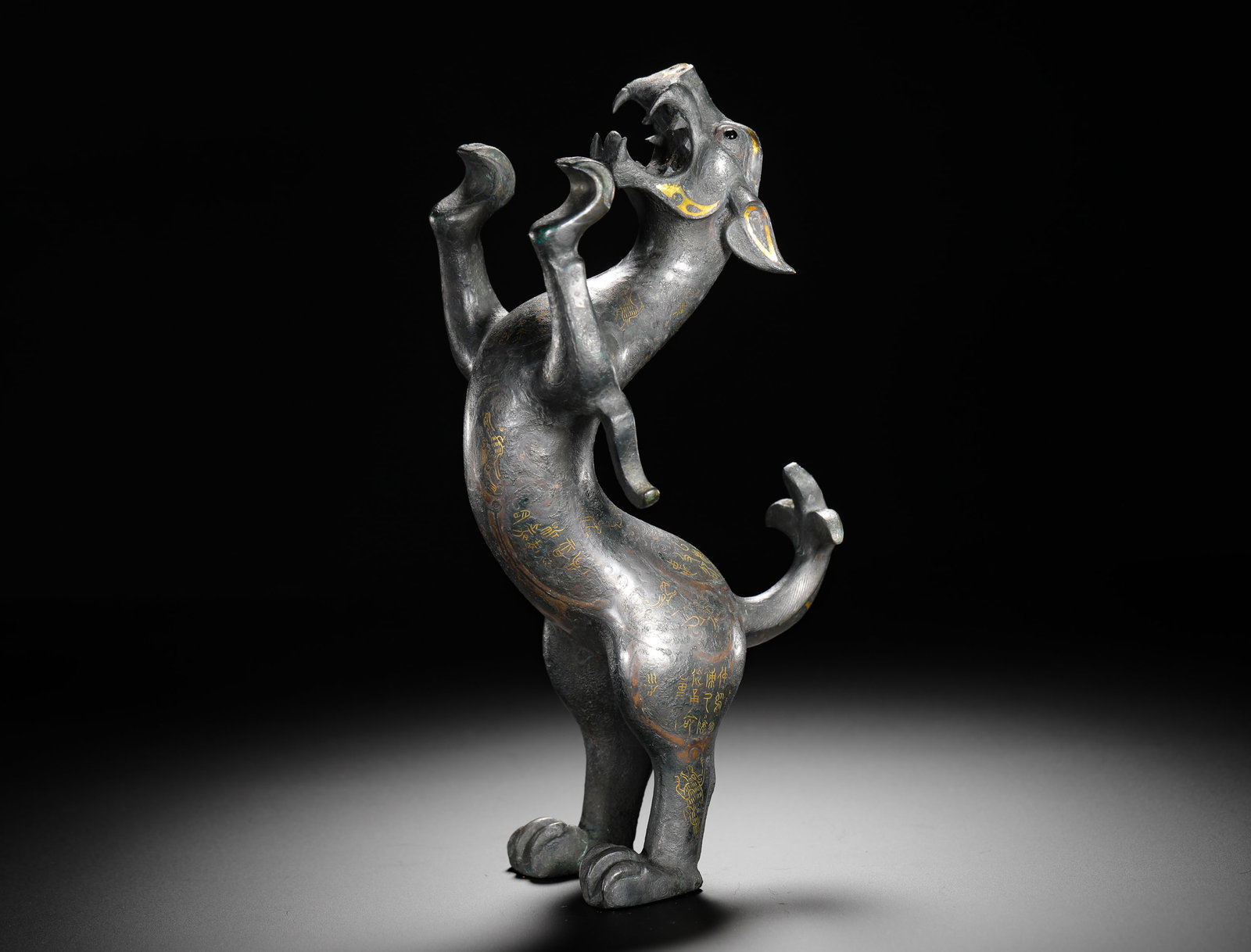 BRONZE INLAID WITH GOLD AUSPICIOUS BEAST FROM THE WARRING STATES PERIOD: Height:23cm(9.06in) Width:10.5cm(4.13in) Weight:1640g(3.62lb)Warring States bronze leaping mythical beast ornament inlaid with gold. Cast in bronze, the beast rears its head and raises its claws in a 