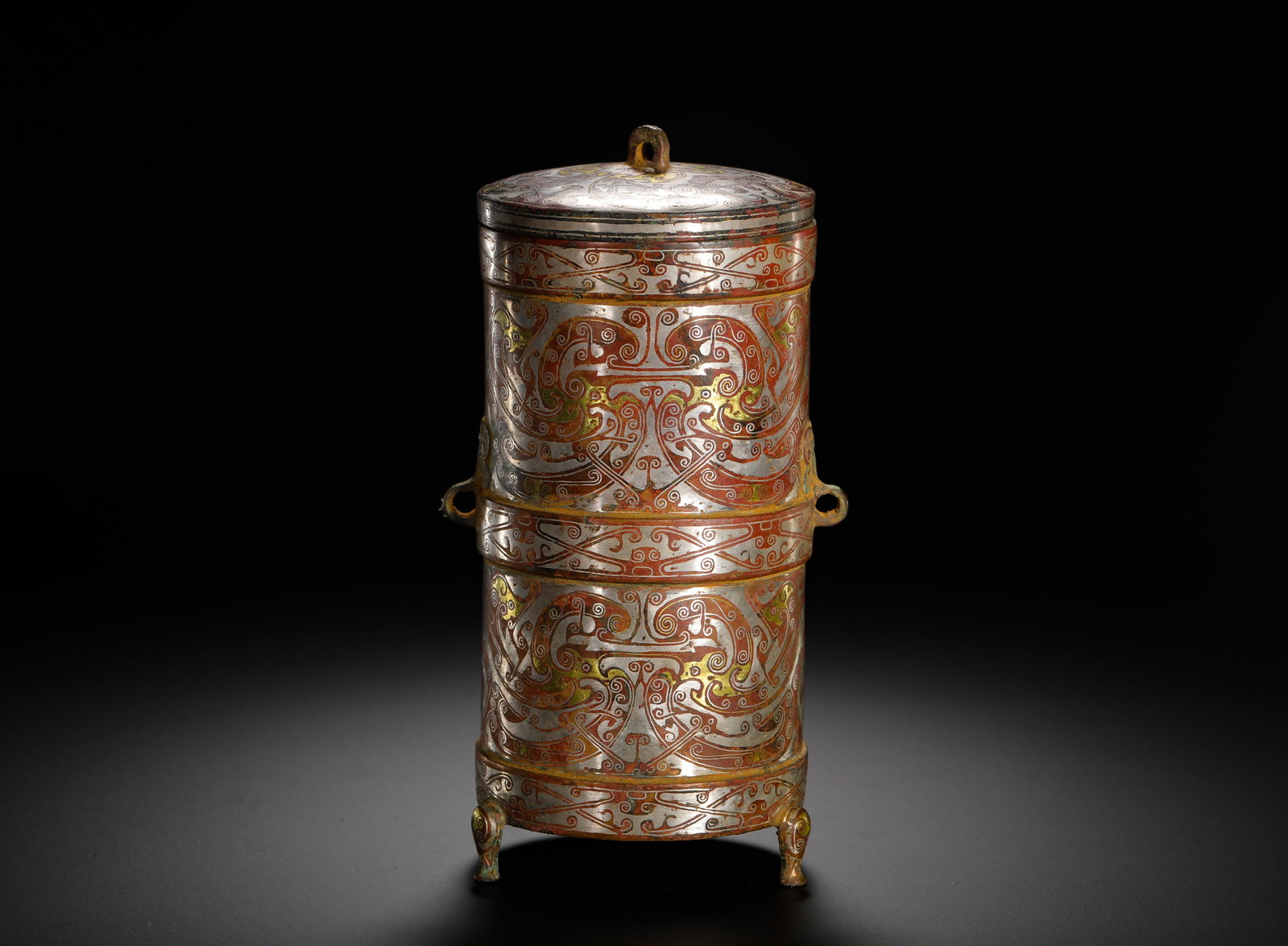 BRONZE WITH INLAID GOLD AND SILVER LIDS FROM THE HAN DYNASTY: Height:17cm(6.69in) Width:9cm(3.54in) Weight:910g(2.01lb)Han Dynasty double-layer bronze covered tripod cylinder inlaid with gold and silver. The vessel is divided into two tiers fully decorated with 