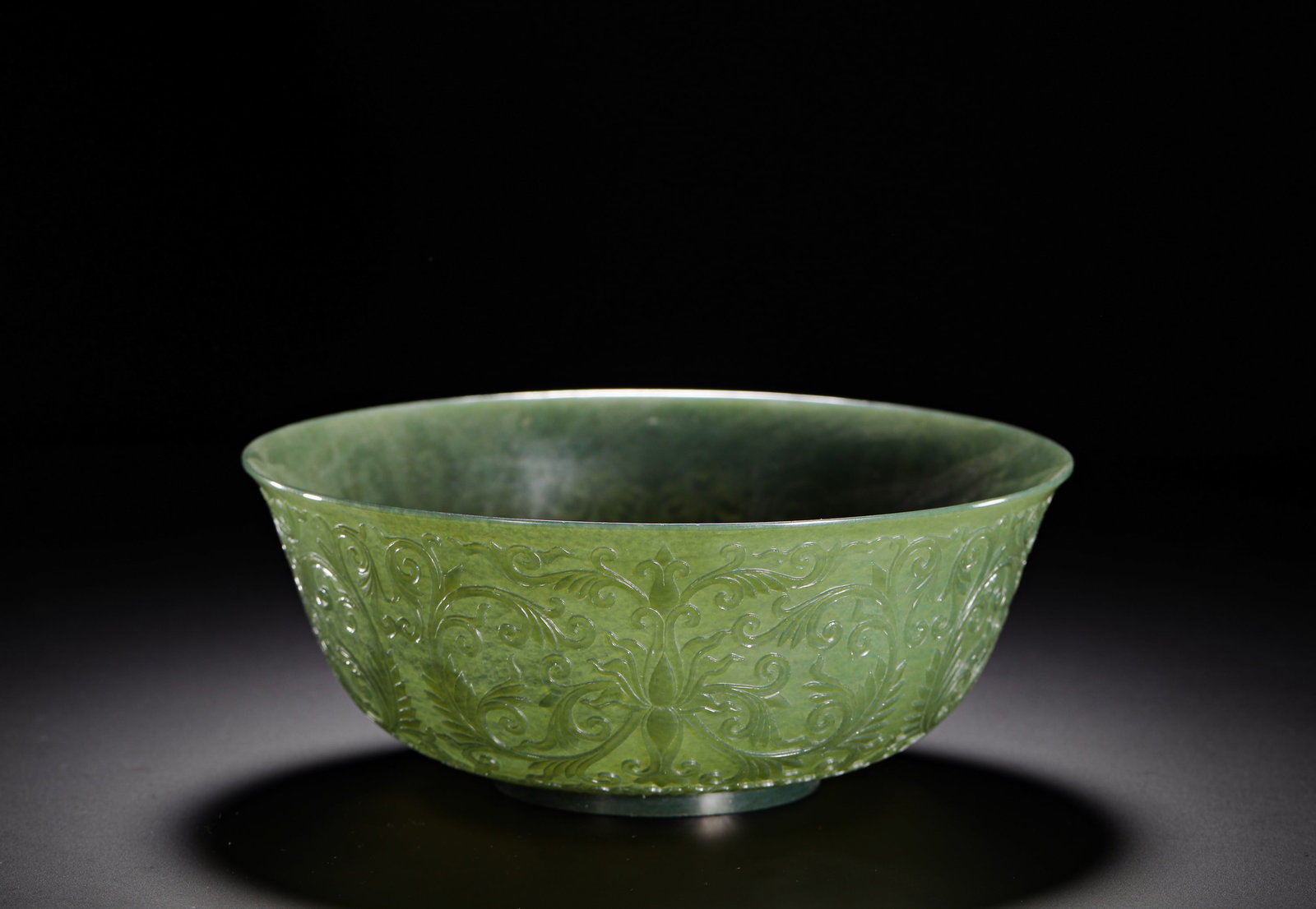 QING DYNASTY HETIAN THIN-WALLED JADE BOWL WITH EMBOSSED PASSIONFLOWER PATTERNS: H:7.5cmW:18.5cmWeight:290gQing Dynasty thinly walled Hetian spinach jade bowl embossed with continuous scrolling lotus patterns, crafted from fine translucent green jade with elaborate floral relief c