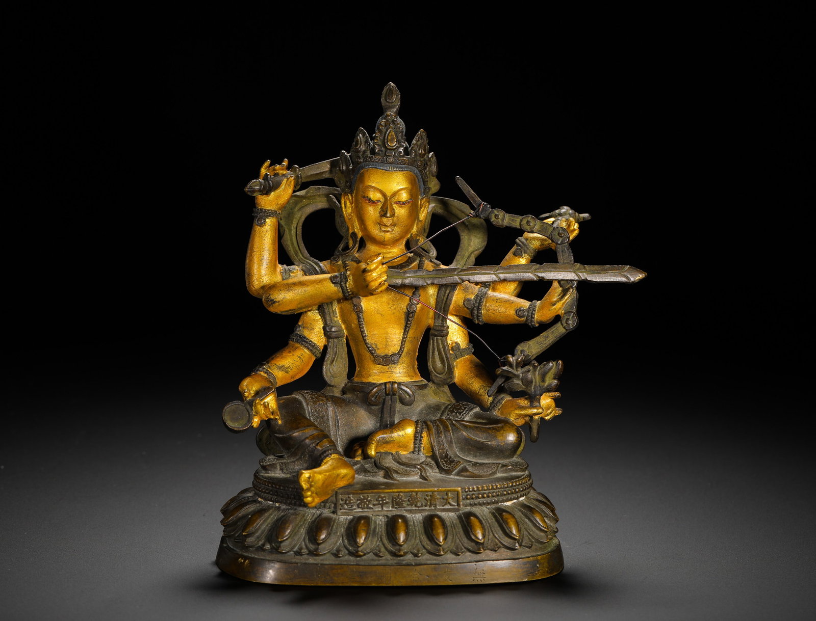 GILDED BRONZE MANJUSRI BODHISATTVA STATUE FROM THE QING DYNASTY: Height:17cm(6.69in) Width:13cm(5.12in) Weight:1370g(3.02lb)Qing Dynasty partially gilded bronze six-armed Manjushri Bodhisattva statue of Qianlong reign, cast from fine brass. Partial gilding covers t