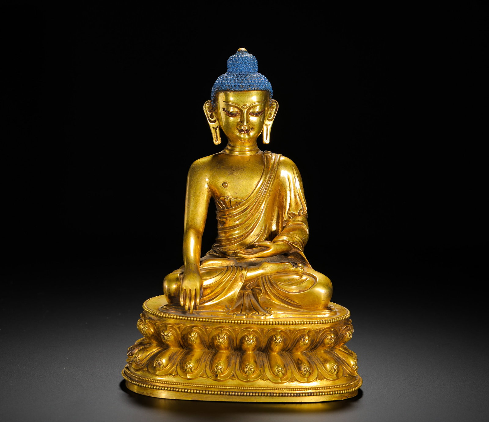 A GILDED BRONZE SEATED STATUE OF SAKYAMUNI FROM THE QING DYNASTY: Height:20cm(7.87in) Width:15cm(5.91in) Weight:2110g(4.65lb)Qing Dynasty fully gilded bronze seated Shakyamuni Buddha statue, entirely cast from fine brass with full gilding. The Buddha sits in full lo