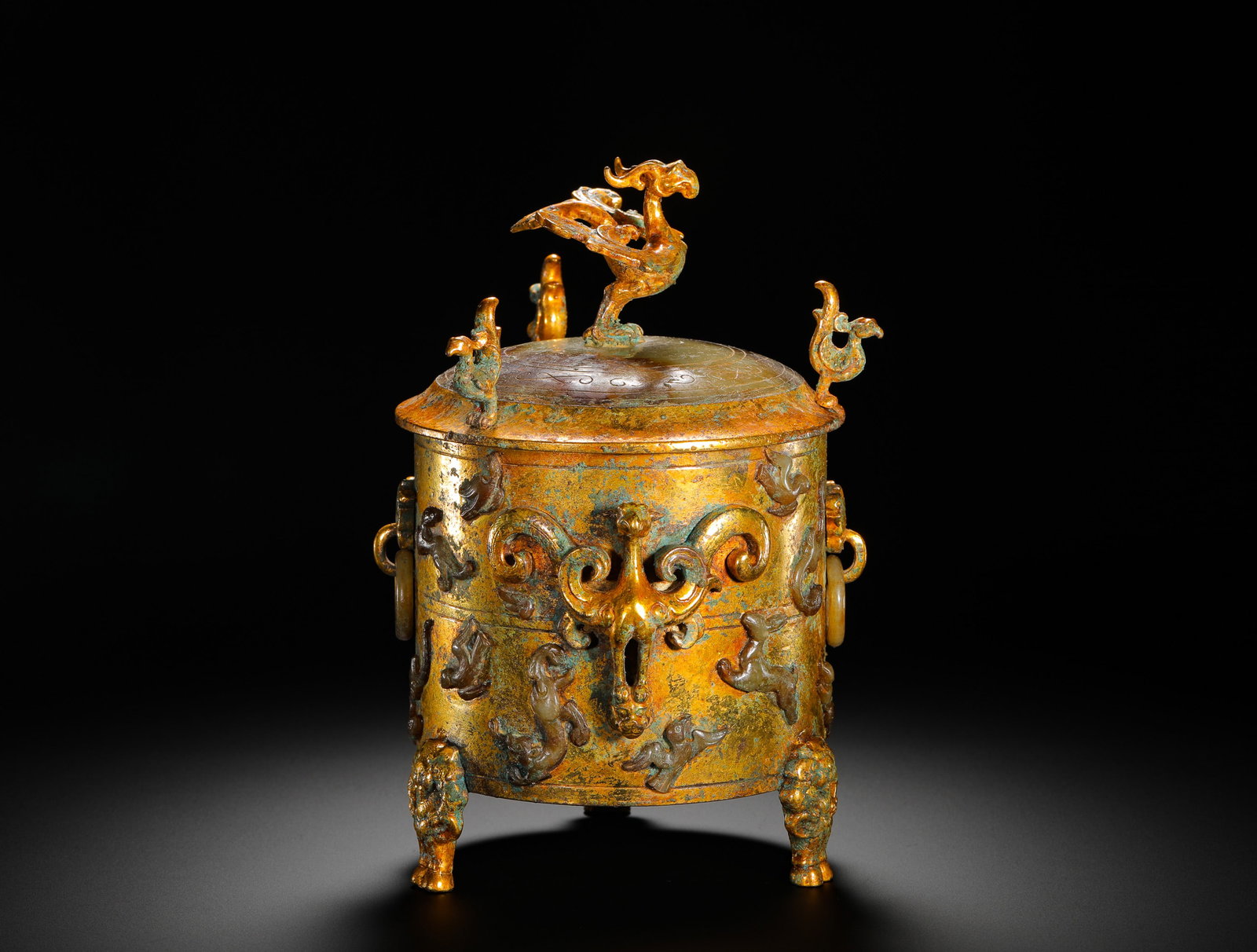 A GILDED BRONZE JAR WITH JADE INLAID AUSPICIOUS BEAST PATTERN FROM THE HAN DYNASTY: Height:20cm(7.87in) Width:13cm(5.12in) Weight:1620g(3.57lb)Han Dynasty gilt bronze three-legged covered zun inlaid with jade mythical beast patterns. The bronze vessel is fully gilded, with carved jad