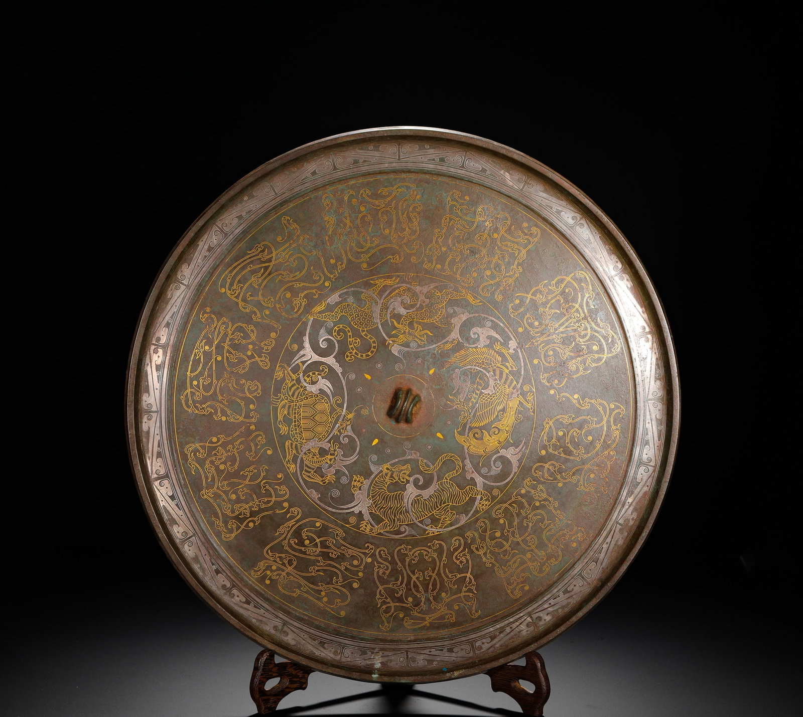 BRONZE MIRROR WITH INLAID GOLD AND SILVER AND FOUR SPIRITS PATTERNS FROM THE HAN DYNASTY: D:30cm(11.81in) Weight:1890g(4.17lb)Han Dynasty bronze mirror inlaid with gold and silver Four Divine Beasts patterns. The center is decorated with gold and silver inlaid Azure Dragon, White Tiger, Ve