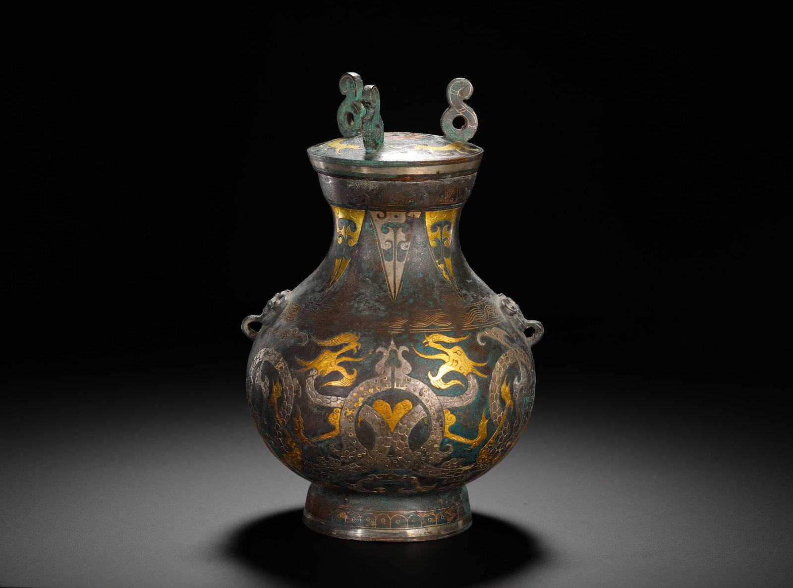 BRONZE INLAID GOLD AND SILVER DOUBLE DRAGON PATTERN TEAPOT FROM THE WARRING STATES PERIOD: Height:19cm(7.48in) Width:13cm(5.12in) Weight:1020g(2.25lb)Warring States bronze wine pot inlaid with gold and silver interlocking dragon patterns, beast-shaped ring handles, lidded with two twisted l