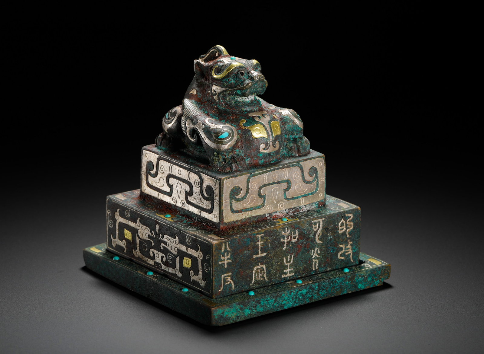 HAN DYNASTY INLAID GOLD AND SILVER INLAID TURQUOISE AUSPICIOUS BEAST SEAL: Height:10cm(3.94in) Width:9.5cm(3.74in) Weight:1340g(2.95lb)Three-tiered bronze master seal of Han Dynasty, inlaid with gold, silver and turquoise. The top knob is a crouching sacred beast with gold-s