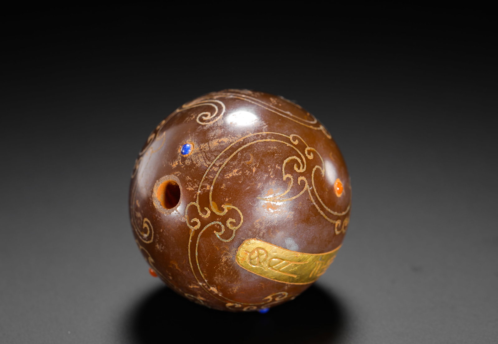 HAN DYNASTY INLAID GOLD AND SILVER WITH GEMSTONES AND AGATE BALLS: D:4cm (1.57in) Weight:100g (0.22lb)This is a Han Dynasty agate ball decorated with gold and silver inlaid cloud patterns and inset with blue and red gems. The intricate craftsmanship exemplifies the o