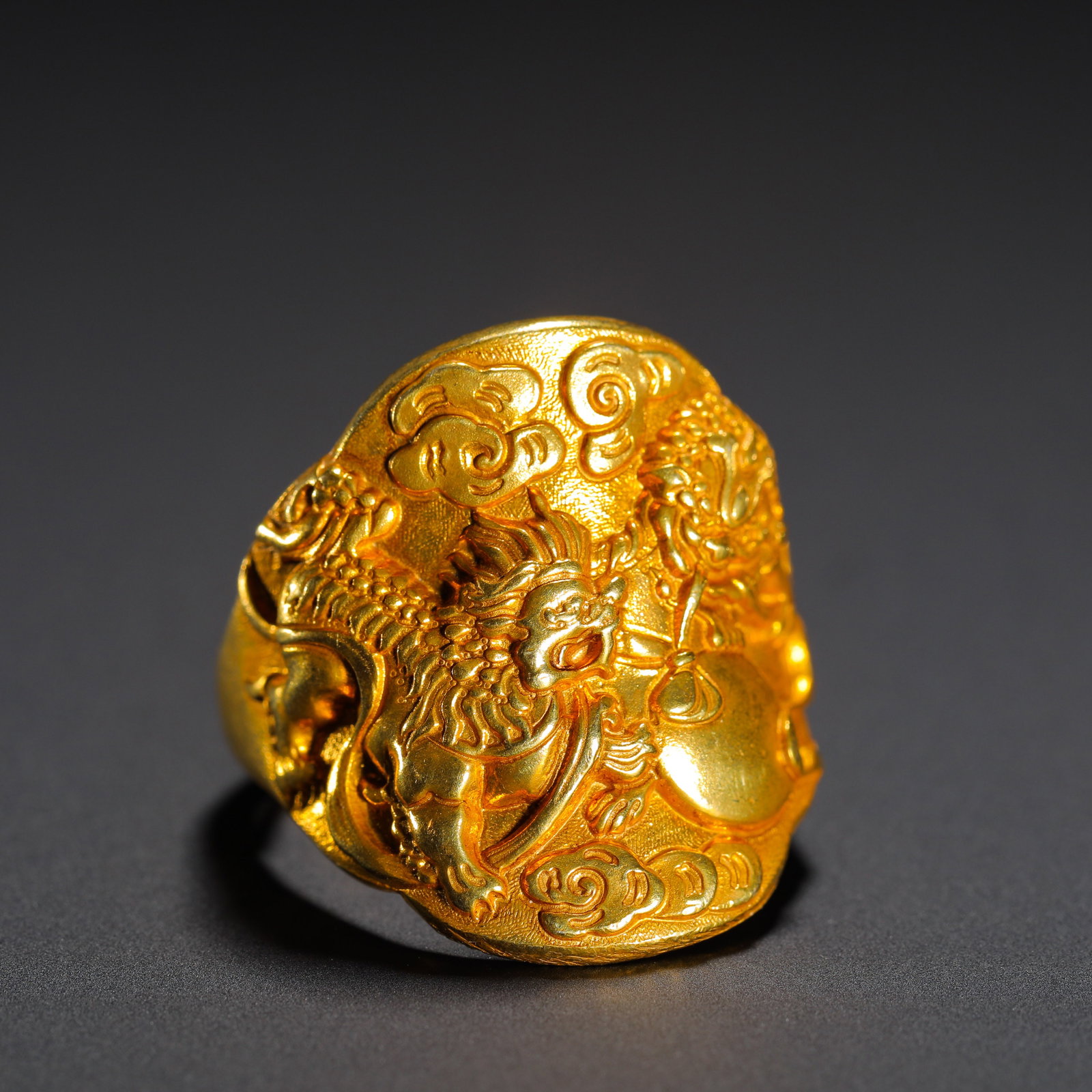 QING DYNASTY GILDED COPPER HIGH RELIEF RING: Diameter:2.5cm(0.98in) Weight:10g(0.02lb)Gilt bronze ring with high-relief twin lions playing ball and cloud pattern, Qing Dynasty. The shield-shaped face is carved with vivid lions and auspicious clo
