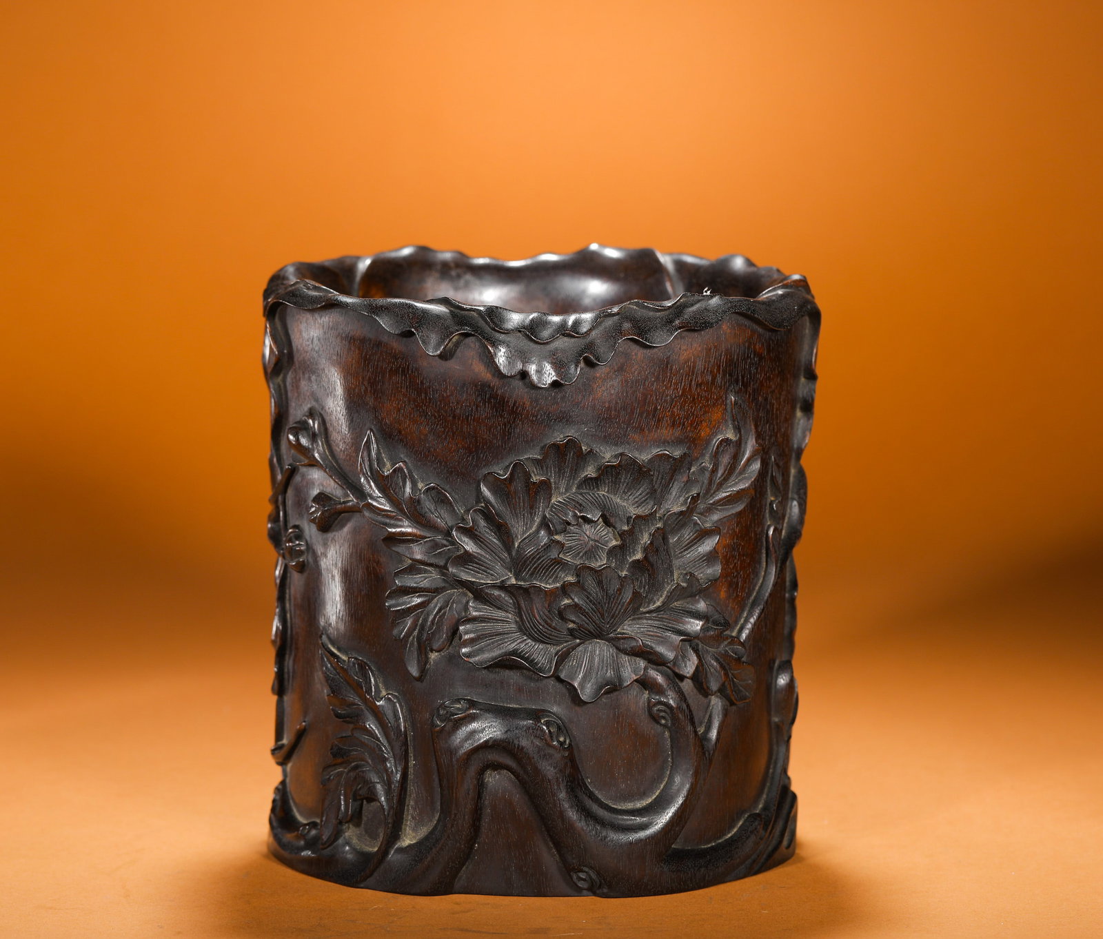 QING DYNASTY PURPLE SANDALWOOD CARVED PEONY-SHAPED PEN HOLDER: Height:18cm(7.09in) Width:17cm(6.69in) Weight:1140g(2.51lb)Qing Dynasty red sandalwood brush pot carved with peony relief, hollowed from a single solid log. The rim is naturally undulating like twiste