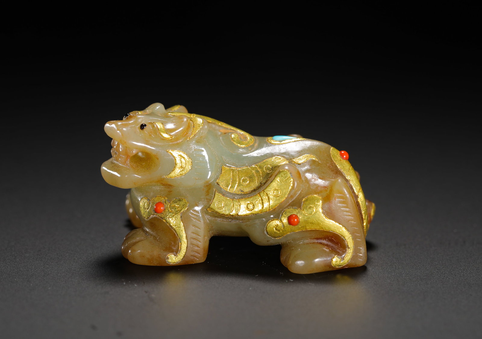 HAN DYNASTY HETIAN JADE INLAID WITH GOLD AUSPICIOUS BEASTS: Height:4.7cm(1.85in) Width:2.5cm(0.98in) Weight:50g(0.11lb)Han Dynasty celadon jade bixie beast ornament with gold wire inlay, turquoise and red gemstones. Solid round carving with spread cloud wings,