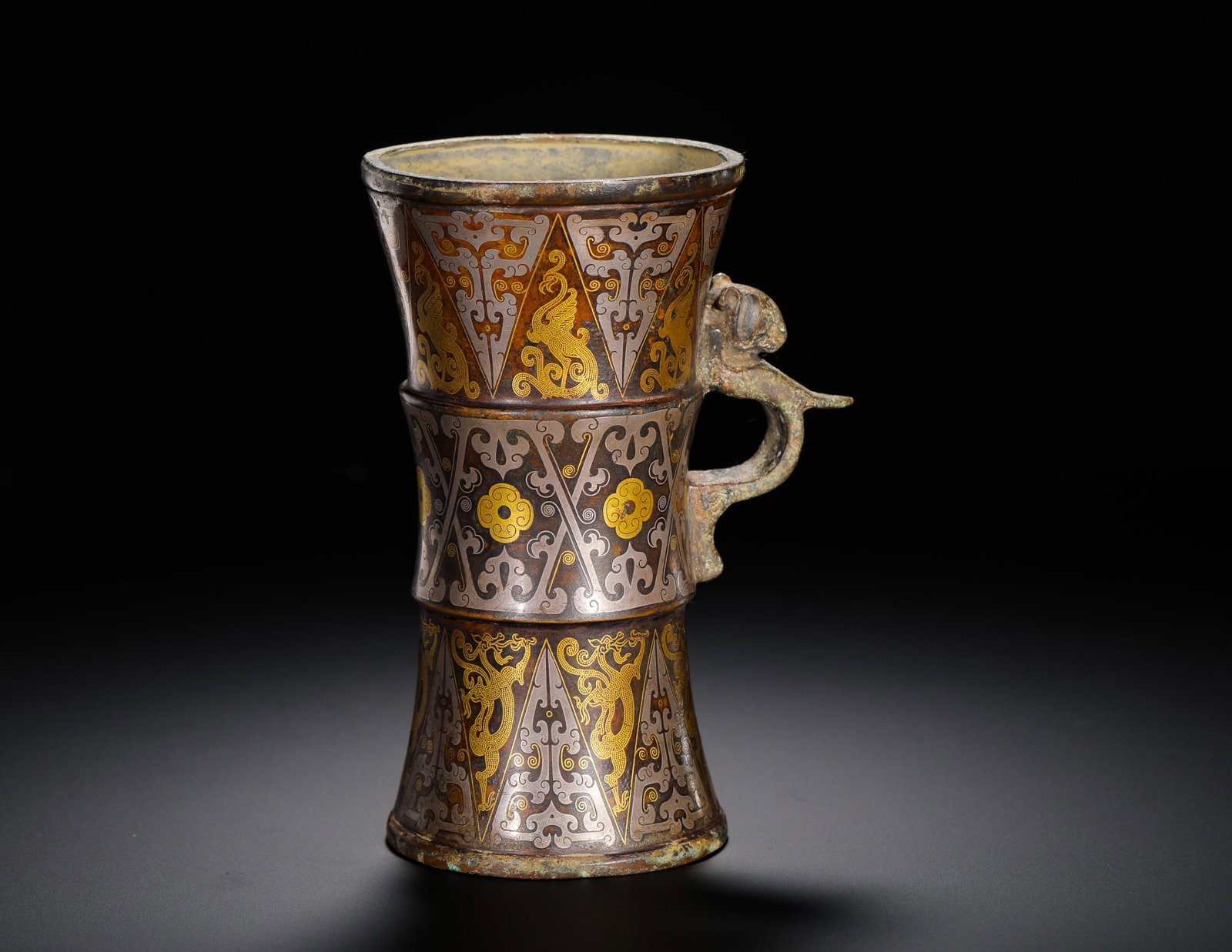 HAN DYNASTY BRONZE INLAID GOLD AND SILVER BAMBOO-SHAPED CHI DRAGON EAR VESSEL: Height:15.5cm(6.10in) Width:11.5cm(4.53in) Weight:640g(1.41lb)Bronze chi-dragon handled ritual vessel shaped like bamboo segments, inlaid with gold and silver. Three-tiered bamboo-joint structure, tri