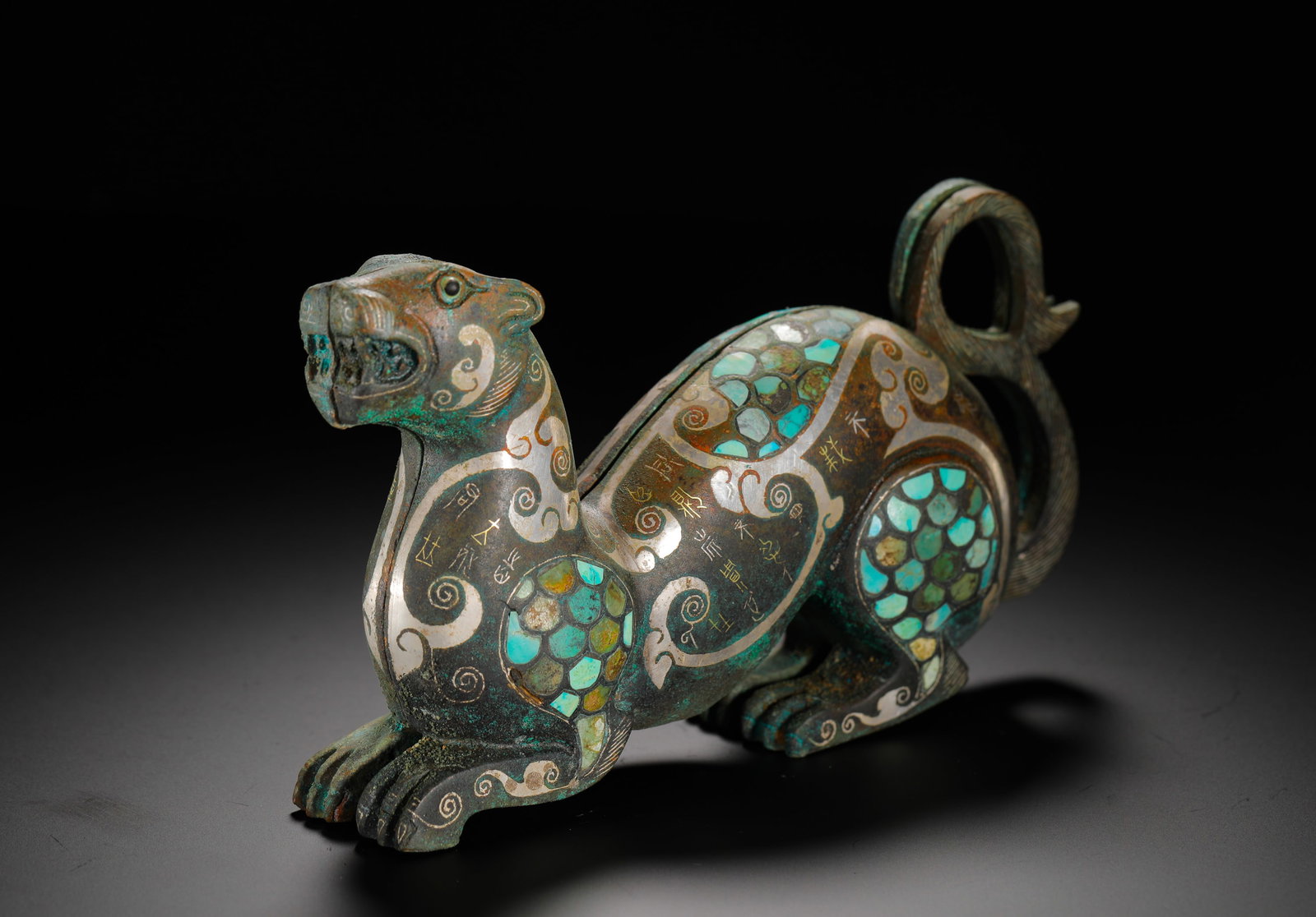 BRONZE OF THE WARRING STATES PERIOD WITH INLAID GOLD AND SILVER INLAID TURQUOISE TIGER SHAPE: H:10cm (3.94in) W:19cm (7.48in) Weight:1680g (3.70lb)This is a Warring States Period ornament. Shaped like a fierce tiger, it is decorated with intricate patterns inlaid with gold, silver, and turquoi