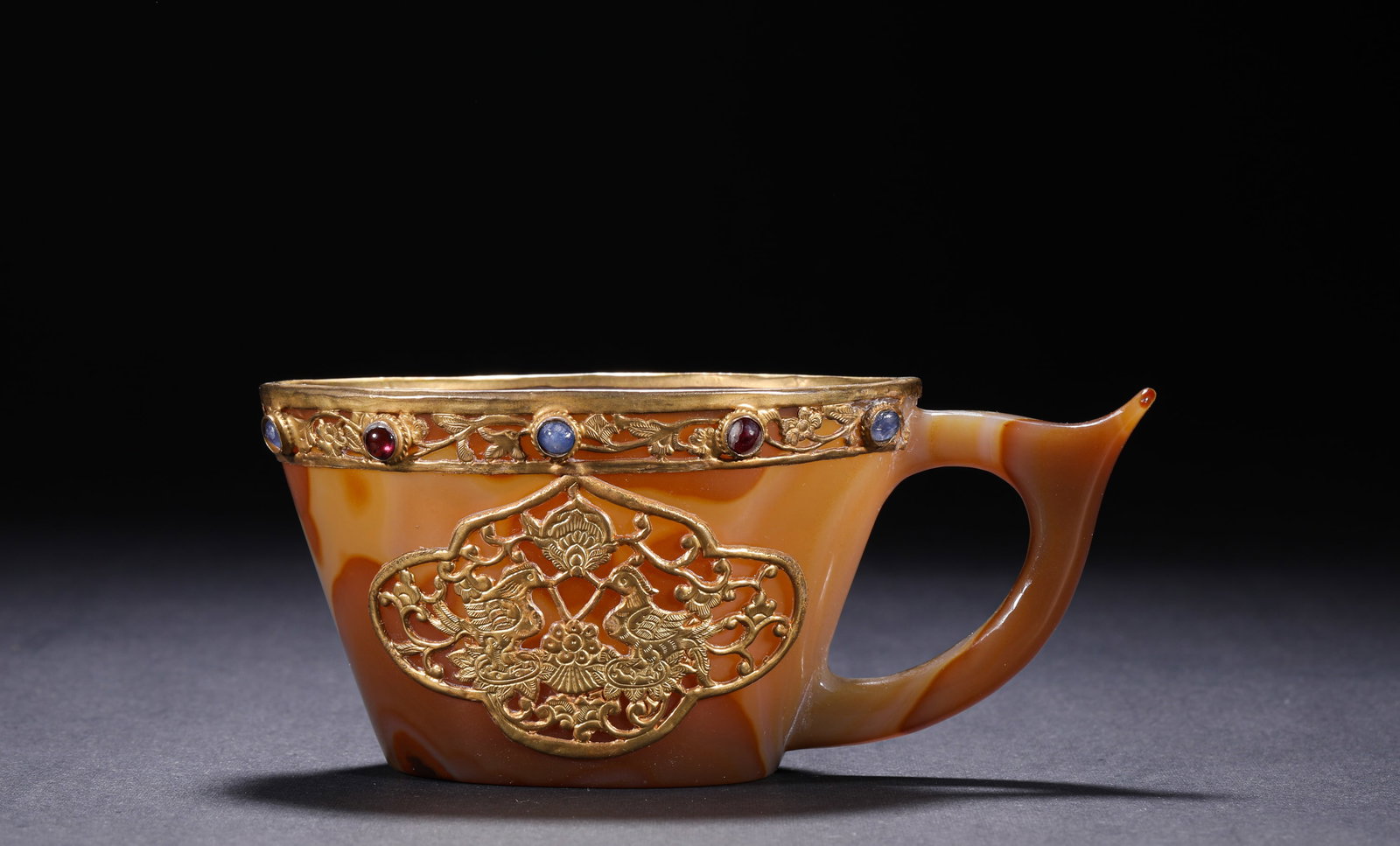 TANG DYNASTY AGATE GOLD-INLAID FLOWER AND BIRD PATTERNED CUP: H:5.5cm(2.17in) W:12.7cm(5.00in) Weight:210g(0.46lb)This cup is a top-tier heavy vessel of Tang Dynasty Silk Road culture. It is carved from a single piece of natural red agate through hollowing. The 