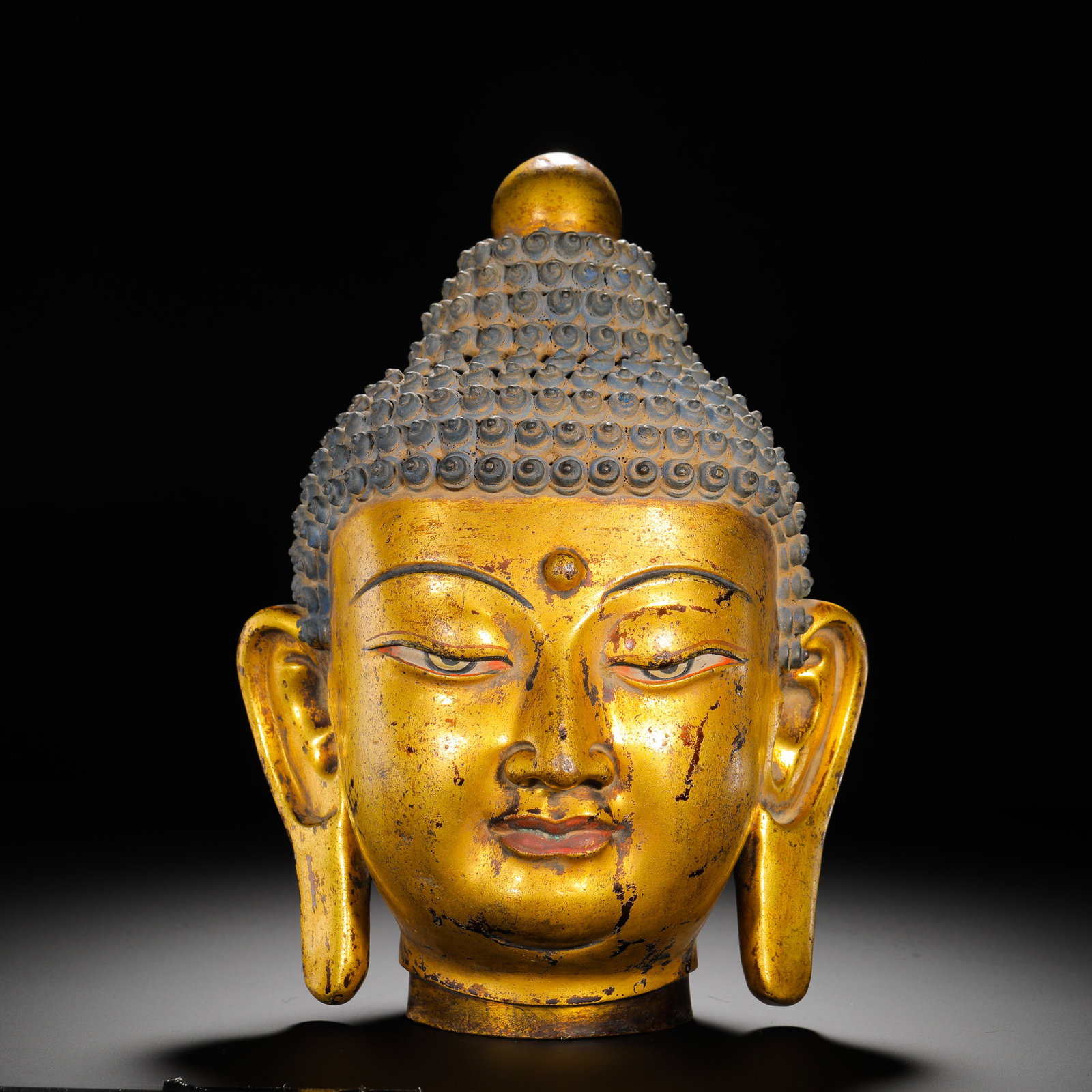 BRONZE GILDED BUDDHA HEAD OFFERINGS FROM THE QING DYNASTY: Height:30cm(11.81in) Width:23cm(9.06in) Weight:4960g(10.93lb)Gilded copper Buddha head offering ornament, Qing Tibetan Buddhism. Fully covered in gilding with rounded ushnisha on top, dense neat spira