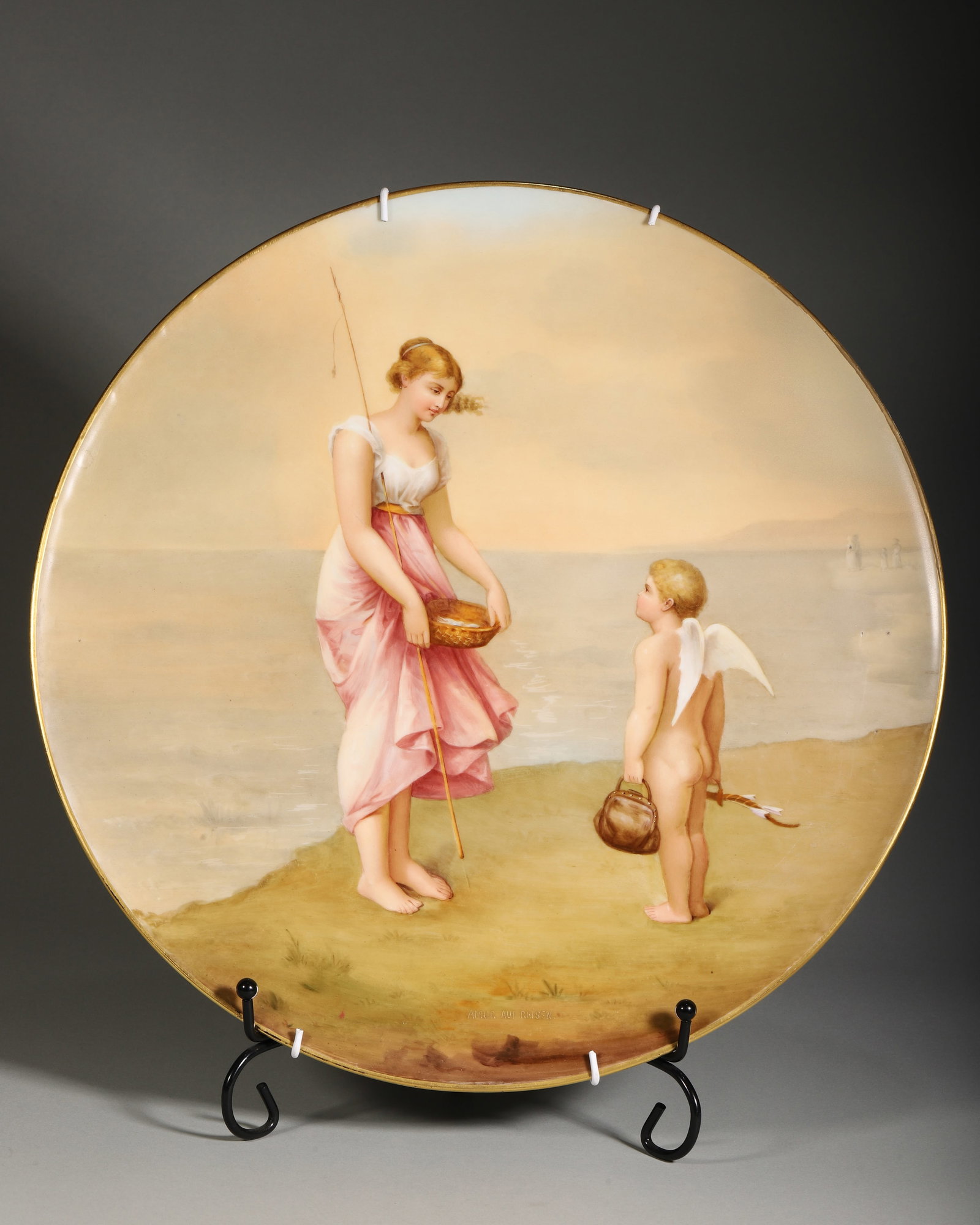 19TH CENTURY AUSTRIAN ROYAL VIENNA HAND-PAINTED PORCELAIN CHARGER, VENUS AND CUPID ON THE SHORE: D 35cm (13.78 in),Heavy-bodied circular porcelain charger with gilded rim. The surface finely painted with a neoclassical mythological scene: Venus fishing by the shore facing Cupid holding bow and ar