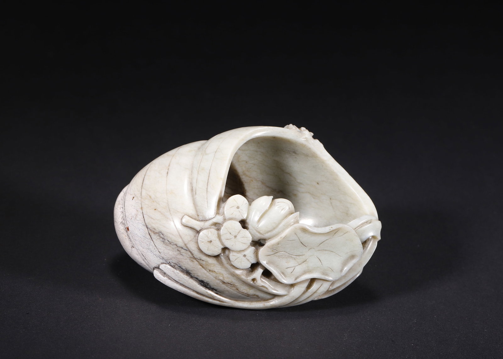 QING DYNASTY BURNT JADE CONCH-FORM WATER COUPE WITH LOTUS AND CRICKET MOTIFS (1636?C1912 AD): L 10.00cm (3.94 in); W 7.00cm (2.76 in); Wt 288.00g (0.63 lb),Qing Dynasty (1636?C1912 AD) Hetian jade water coupe carved as a single conch shell, artificially treated to pale grey-white burnt jade to