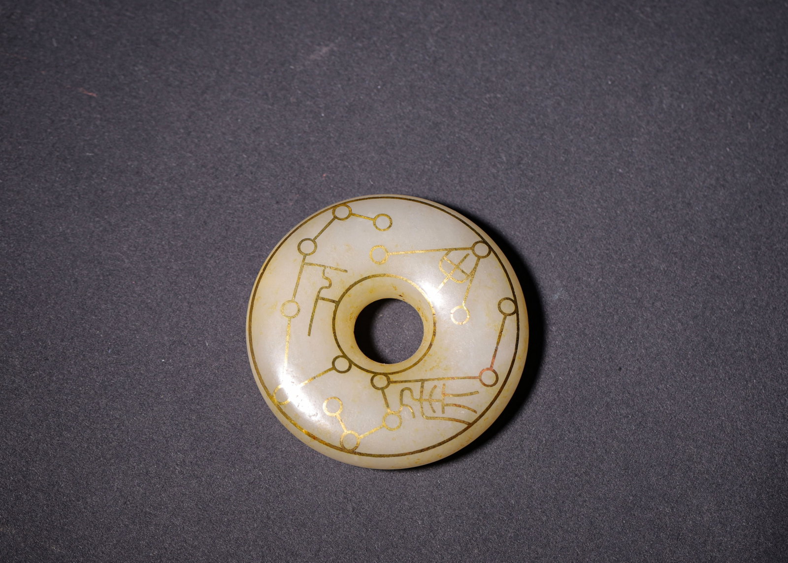 HETIAN JADE PING'AN KOU WITH GOLD INLAID ASTRONOMICAL DIAGRAM AND TALISMAN SCRIPT, HAN DYNASTY (202: D 5cm (1.97 in); Wt 56g (0.12 lb),Carved from Hetian jade in smooth Ping'an Kou form. Both sides adorned with gold inlay depicting star constellations and archaic talisman characters, enclosed by doub