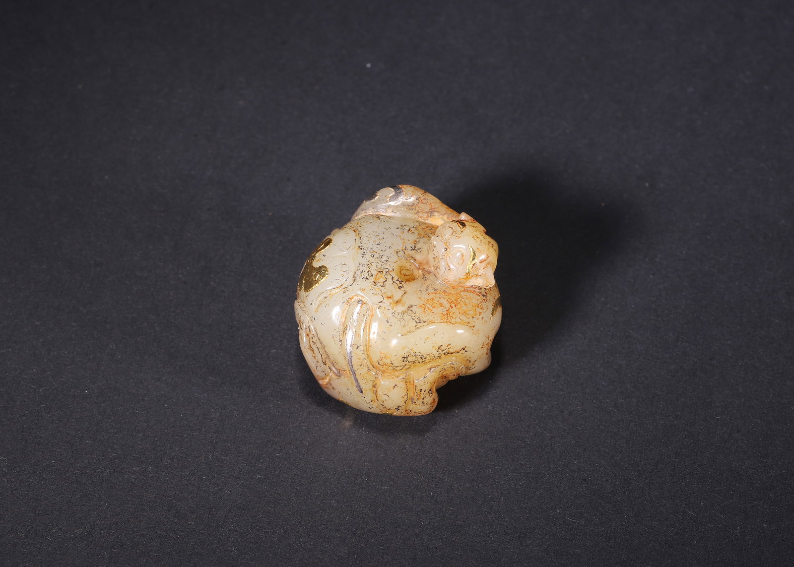 A WHITE JADE MYTHICAL BEAST PENDANT WITH GOLD AND SILVER INLAY, HAN DYNASTY: L 3.50cm (1.38 in); W 3.20cm (1.26 in); H 2.80cm (1.10 in); Wt 42.00g (0.09 lb),Carved from white nephrite, covered with russet patina. Coiled mythical beast form, decorated with gold and silver inlai