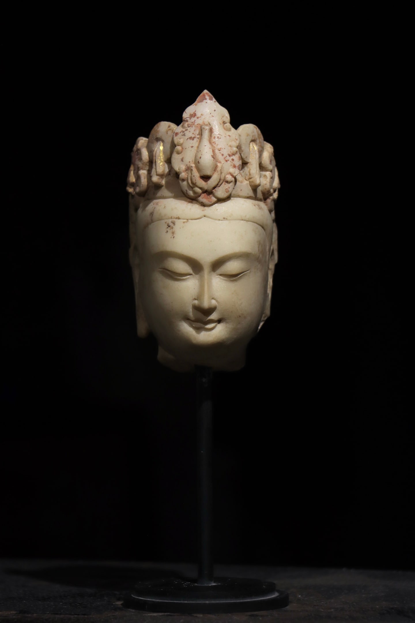 PAINTED AND GILDED WHITE MARBLE HEAD OF BODHISATTVA WITH VASE MOTIF, TANG DYNASTY (618?C907 AD): Net H 14cm (5.51 in),Head of Bodhisattva carved from white marble with lustrous pale tone. The face is gentle and plump, eyes softly lowered with subtle tranquil smile, embodying peaceful aura. Adorne