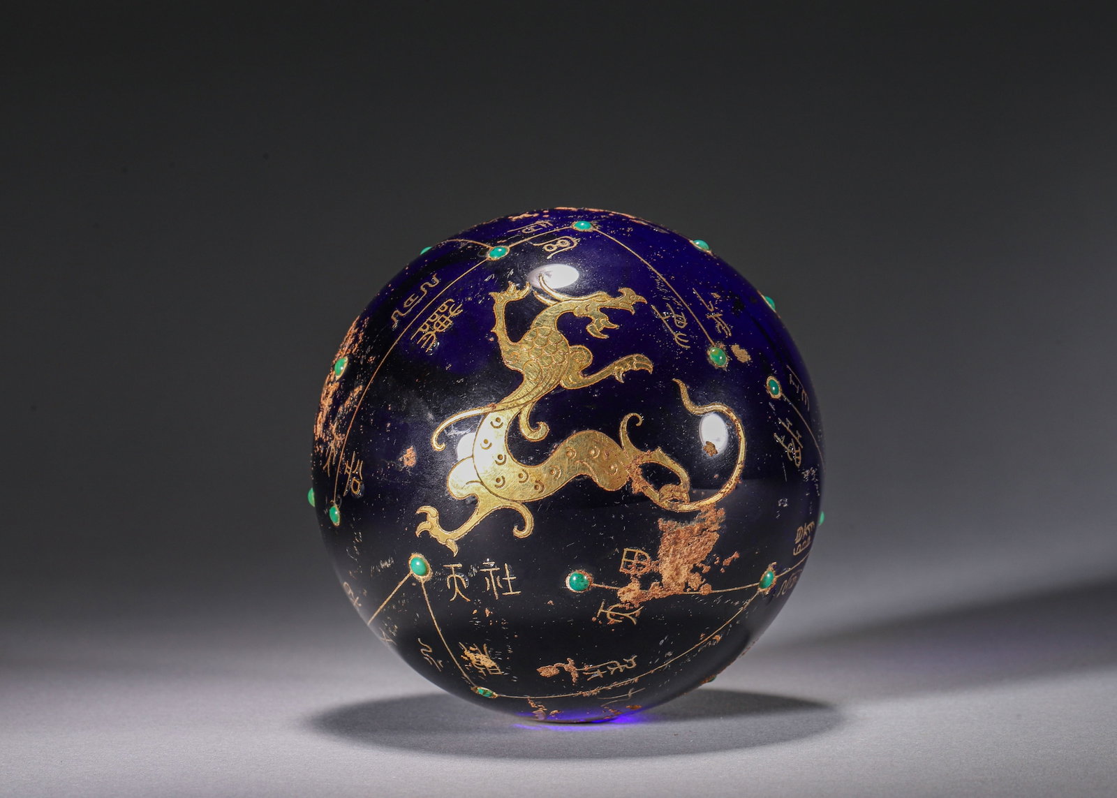 BLUE GLASS CELESTIAL SPHERE WITH GOLD INLAY, TURQUOISE AND FOUR SYMBOLS MOTIFS, HAN DYNASTY (202: D 9.6cm (3.78 in); Wt 1284g (2.83 lb),This celestial sphere is crafted from deep blue glass. Its surface features gold inlaid constellation lines and archaic star names, overlaid with gilded motifs of