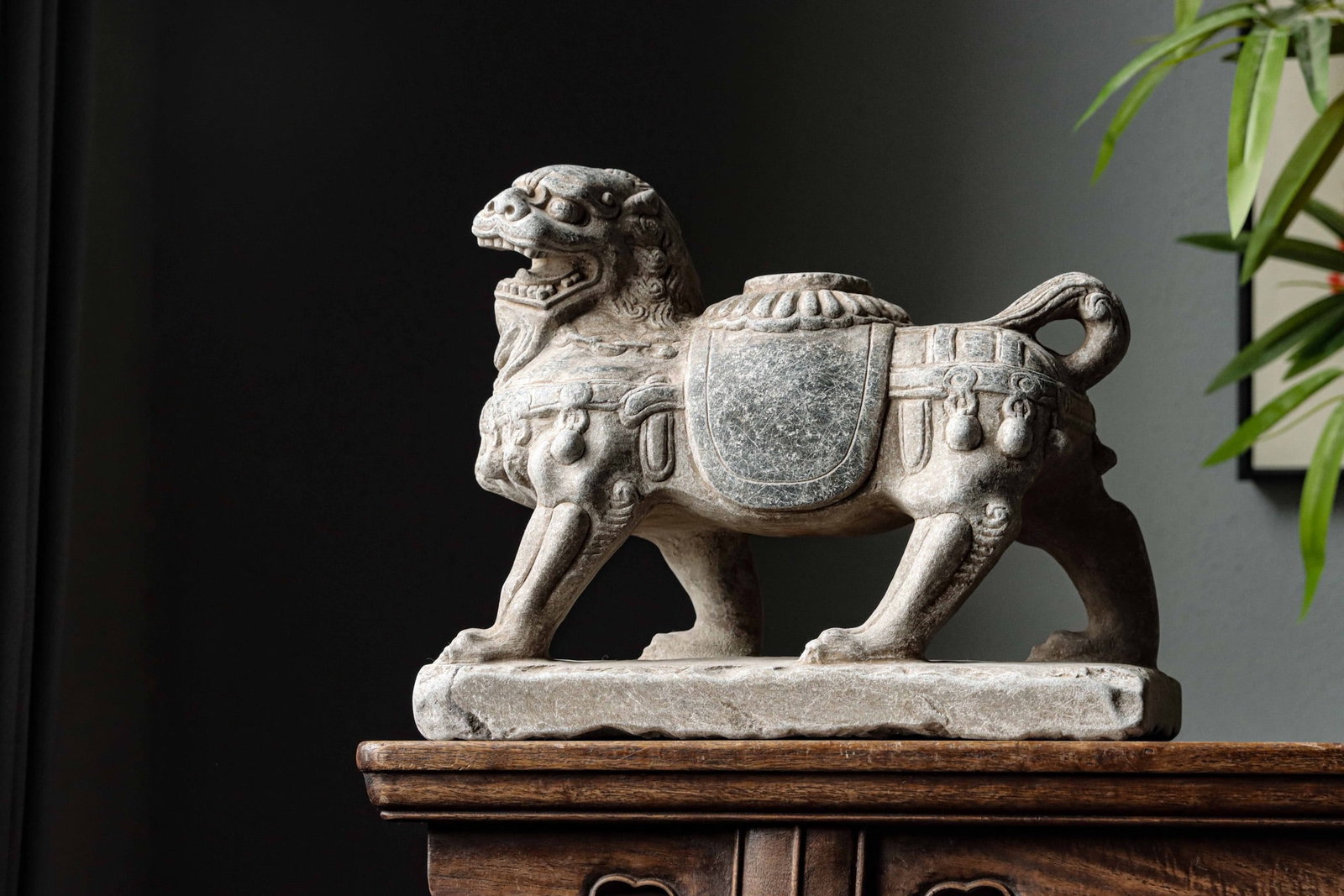BLUESTONE LION CENSER, QING DYNASTY (1644-1912 AD): H 25cm (9.84 in); L 29cm (11.42 in); W 14cm (5.51 in),Carved from a single bluestone block. The lion strides forward with open jaws and curling mane. It is adorned with saddle trappings and hanging be