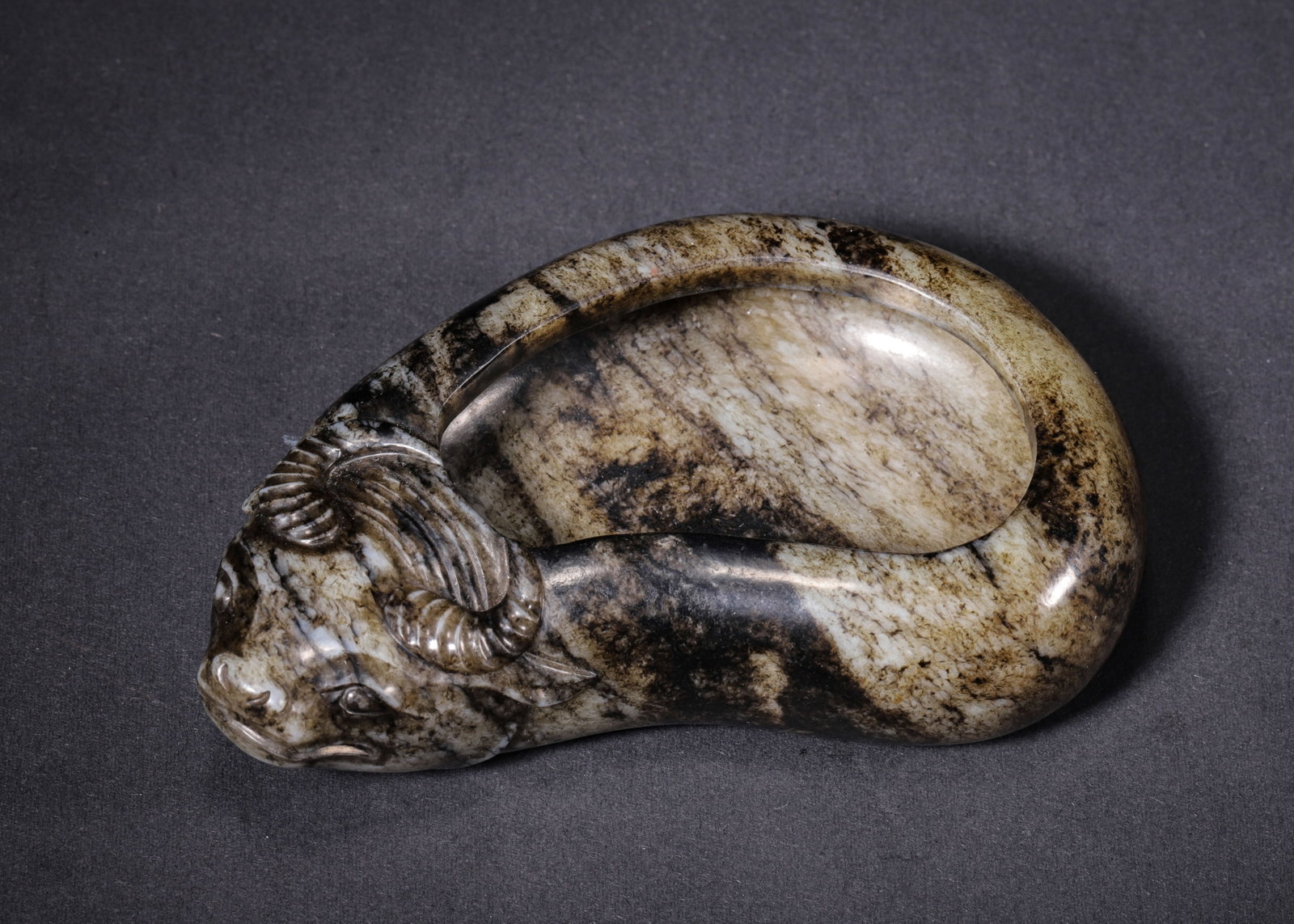 JADE BUFFALO-SHAPED WATER WASHER WITH ANCIENT ARTIFICIAL PATINA, MING DYNASTY (1368-1644 AD): L 12cm (4.72 in); W 7cm (2.76 in); H 3cm (1.18 in); Wt 312g (0.69 lb),Carved from Hetian jade, extensively covered with ancient artificial black-brown patina. Fully modelled recumbent buffalo; the coi