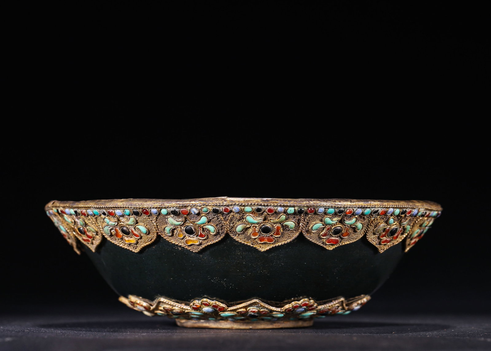 HETIAN SPINACH JADE BOWL WITH GOLD GRANULATION AND INLAID GEMSTONES, TANG DYNASTY (618?C907 AD): D 16cm (6.299 in); H 5cm (1.97 in); Wt 441g (0.97 lb),Hollowed from Hetian spinach jade to form a circular bowl. The exterior is mounted with gold granulated lotus-petal plaques inlaid with turquoise,