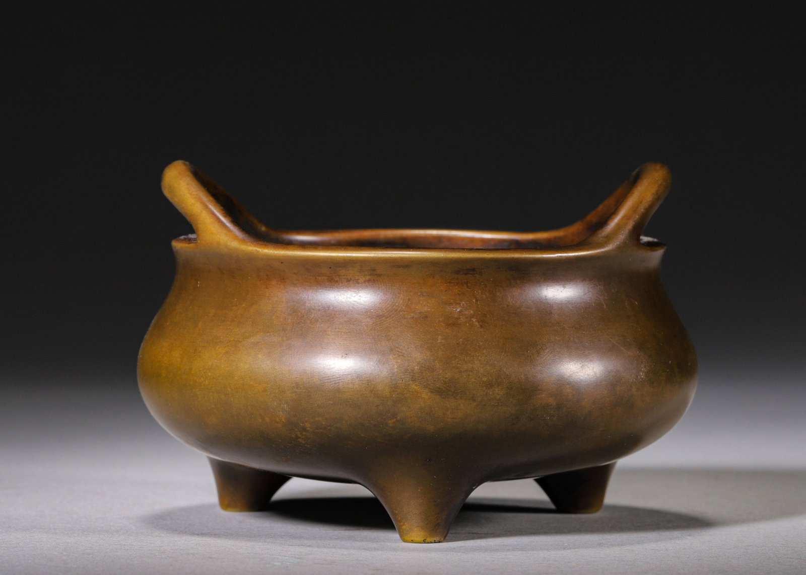 MING DYNASTY BRONZE TRIPOD CENSER WITH UPRIGHT LOOP HANDLES, SEAL SCRIPT "XUANDE?? MARK: D 10cm (3.94 in); H 6cm (2.36 in); Wt 394g (0.87 lb),Cast from fine bronze, the censer features a plump rounded body with a pair of elegant upright loop handles, supported by three tapered mammiform f