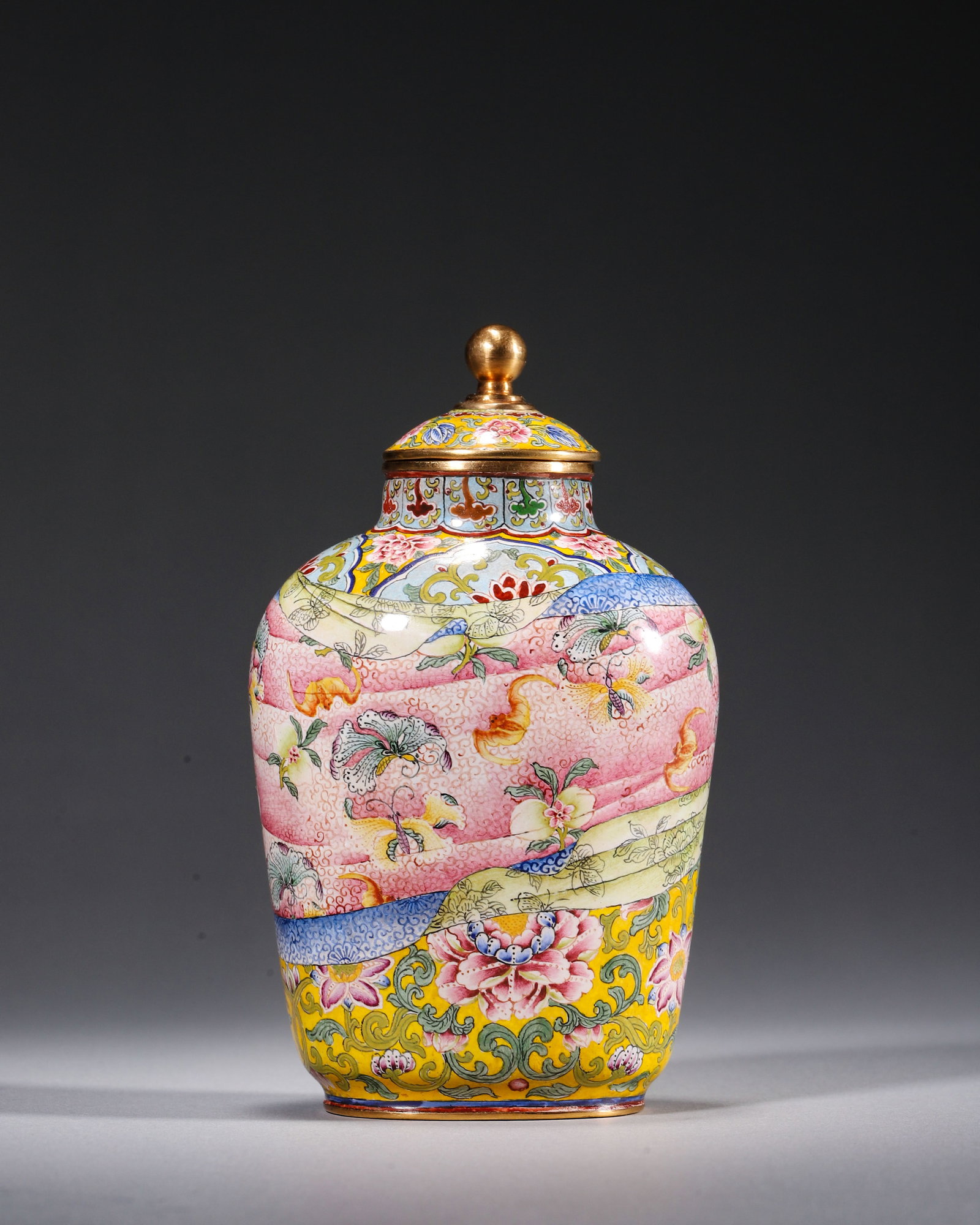 COPPER-BODY PAINTED ENAMEL COVERED JAR WITH ROBE-BUNDLE MOTIF, YONGZHENG PERIOD, QING DYNASTY: L 7cm (2.76 in); W 5.5cm (2.17 in); H 12cm (4.72 in); Wt 250g (0.55 lb),Copper body decorated with painted enamel, fitted with gilded knobbed cover. Ground painted in yellow with scrolling peonies. Th