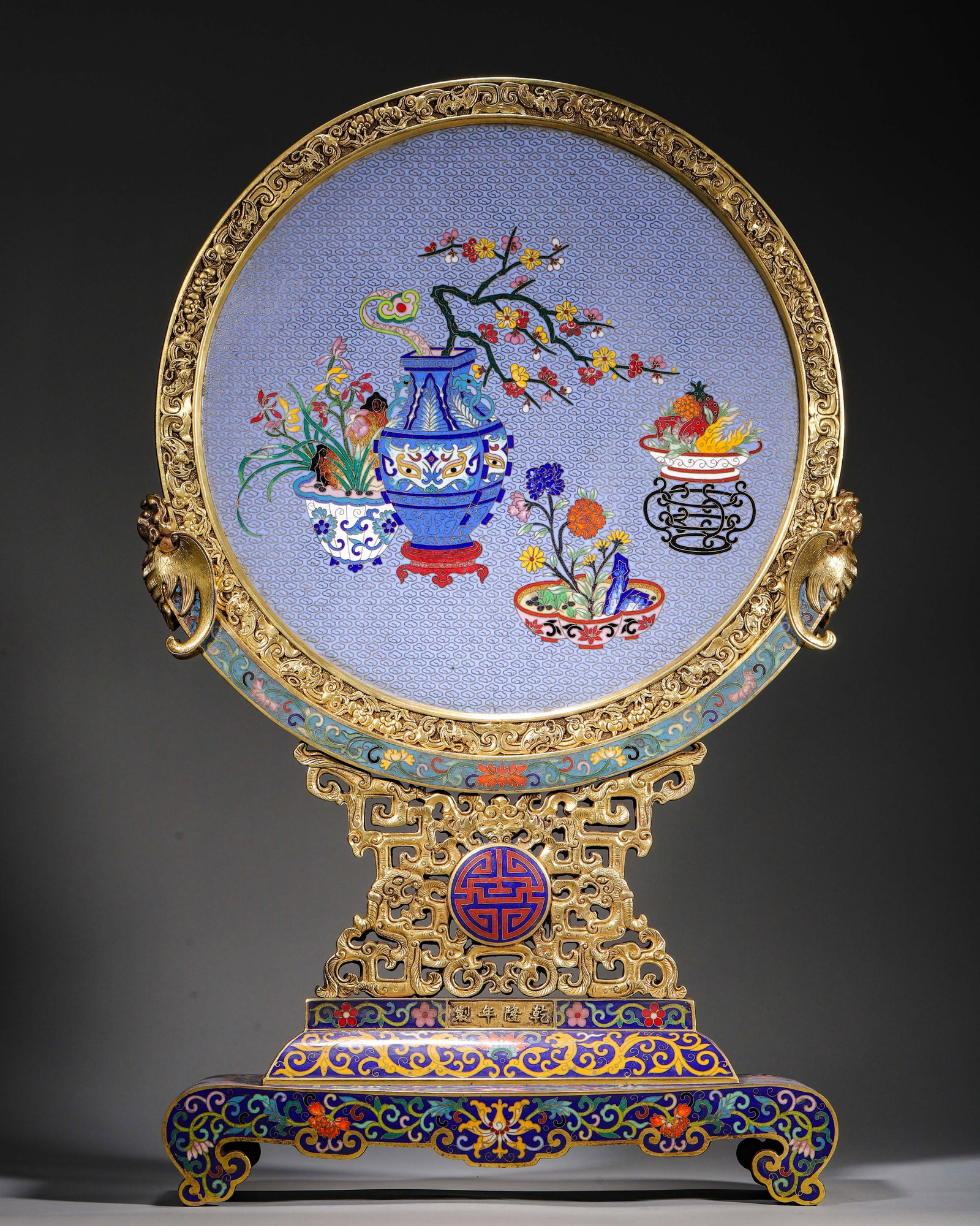 A GILT BRONZE CLOISONNE ENAMEL DOUBLE-SIDED CIRCULAR TABLE SCREEN, QIANLONG MARK, QING DYNASTY: L 37.00cm (14.57 in); W 11.00cm (4.33 in); H 58.00cm (22.83 in); Wt 13300.00g (29.32 lb),Gilt bronze frame, double-sided cloisonne enamel antique offerings. One side plum vase, orchid and fruits; reve