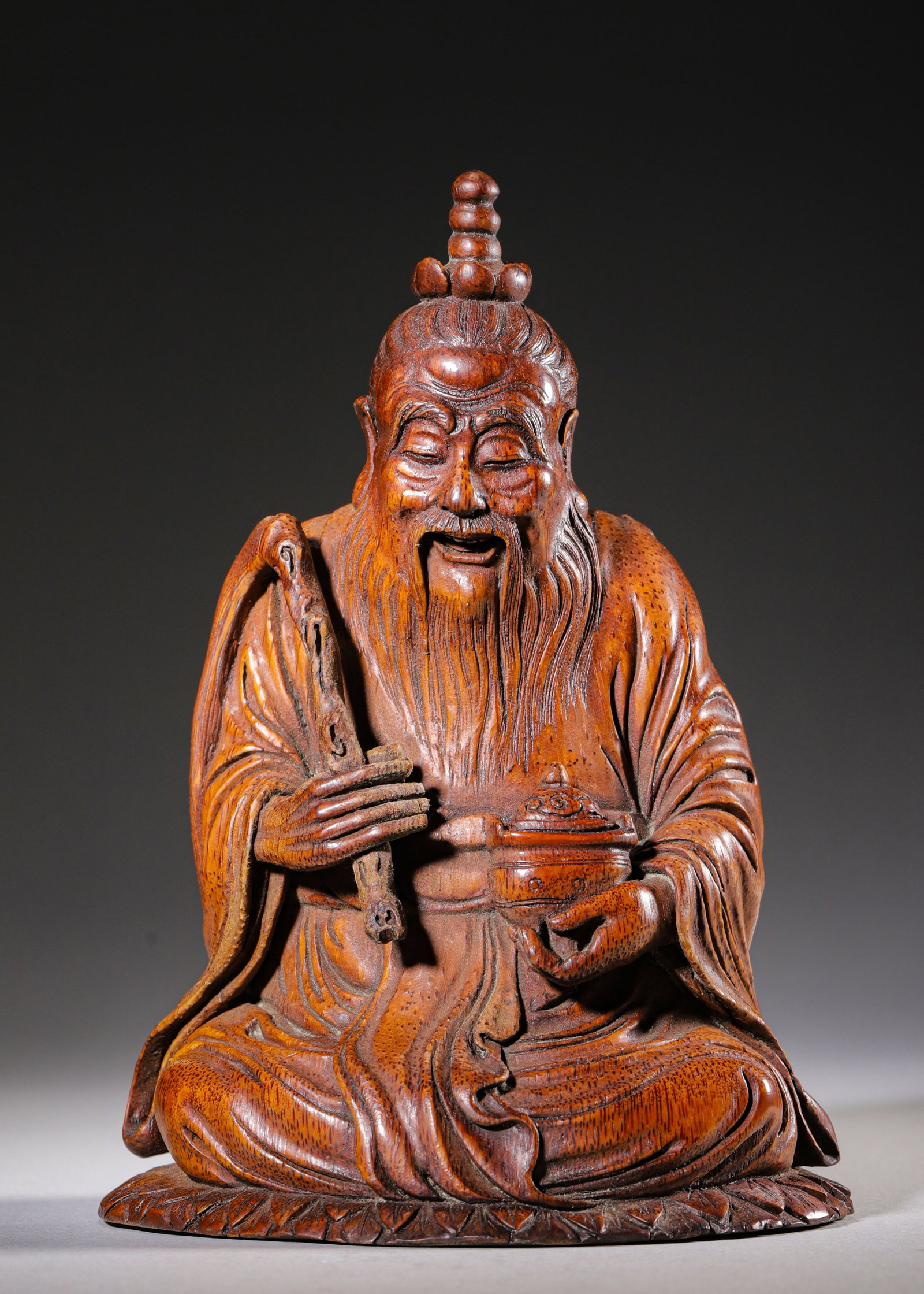 CARVED BAMBOO SEATED FIGURE OF LAOZI, QING DYNASTY (1644-1912 AD): L 14cm (5.51 in); W 11cm (4.33 in); H 20cm (7.87 in); Wt 336g (0.74 lb),Carved from a single bamboo root. Laozi seated in cross-legged pose with Taoist topknot and long beard, serene expression. One h