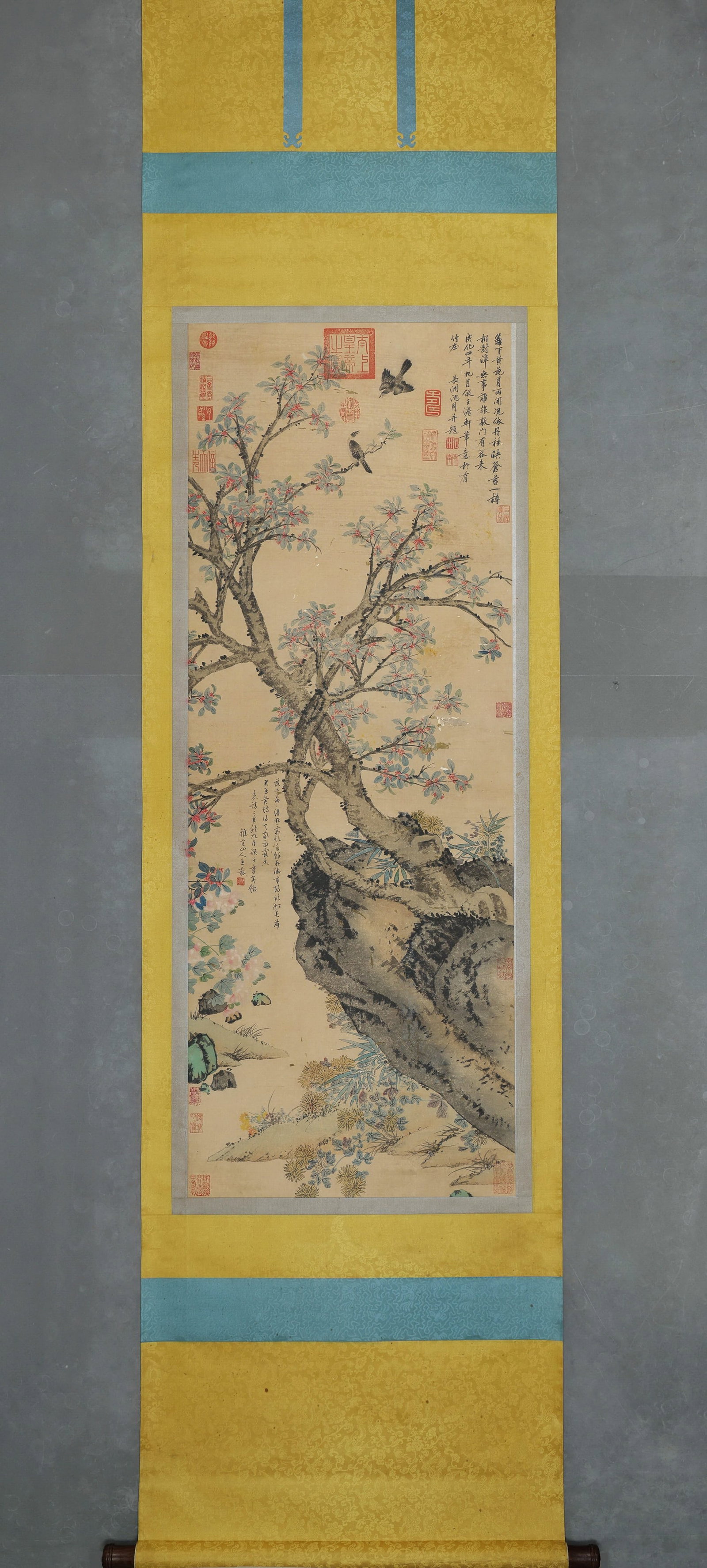 WANG ZHIDENG & SHEN ZHOU, OSMANTHUS, ROCK AND SINGING BIRDS, COLOUR ON PAPER, HANGING SCROLL, MING: Image L 136cm (53.54 in) x Image W 52cm (20.47 in),Flower-and-bird painting in colour on paper. A gnarled osmanthus tree bears clusters of blossoms, alongside rugged lake rock chrysanthemums, bamboo a