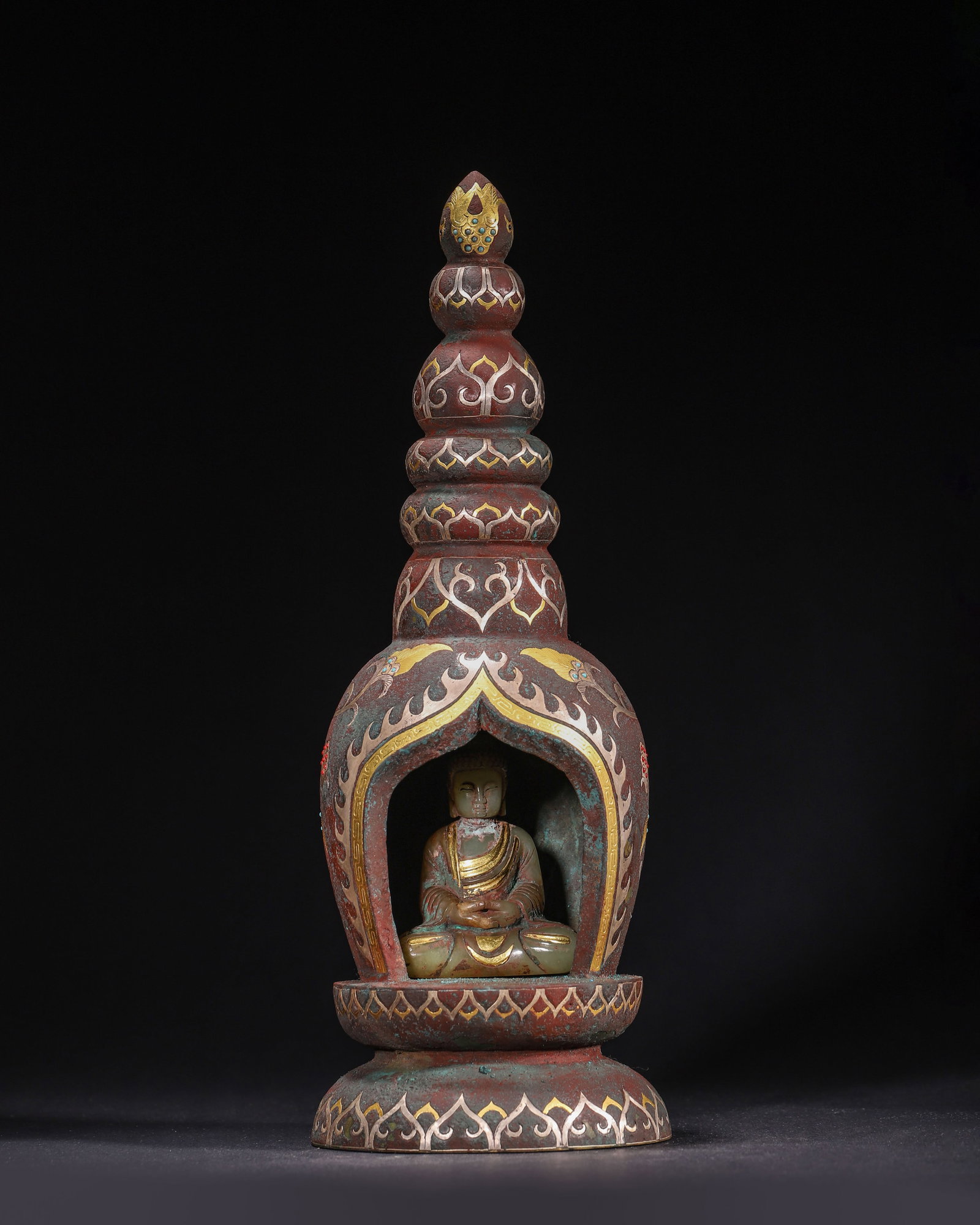 BRONZE NICHE STUPA WITH GOLD AND SILVER INLAY, INSET GILDED HETIAN JADE SHAKYAMUNI, HAN DYNASTY (202: H 30cm (11.81 in); Overall D 11cm (4.33 in); Wt 1922g (4.24 lb),Cast bronze stupa-shaped niche decorated with gold and silver inlaid scrolling flora and avian motifs, embellished with coloured inlays.
