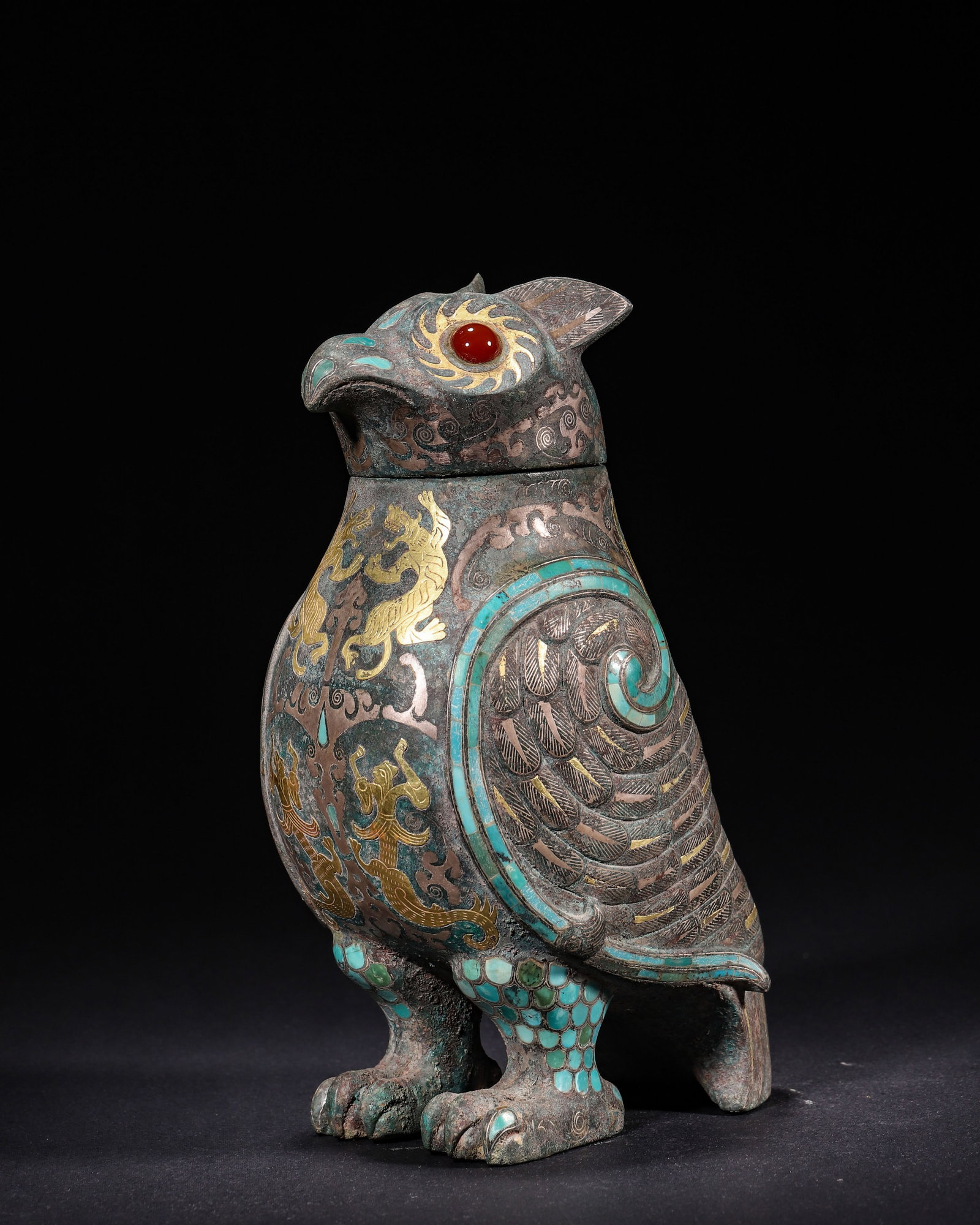 BRONZE OWL-SHAPED ZUN INLAID WITH GOLD, SILVER, TURQUOISE AND AGATE, HAN DYNASTY (202 BC?C220 AD): H 20cm (7.87 in); L 11cm (4.33 in); W 9cm (3.54 in); Wt 1269g (2.80 lb),Cast bronze owl-shaped zun with removable lid. Round eyes inset with red agate. The vessel decorated with gold and silver inlaid