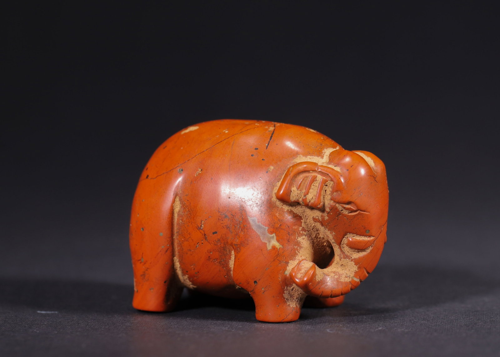RED AGATE ELEPHANT PENDANT, HAN DYNASTY (202 BC-220 AD): H 4.3cm (1.69 in); L 5.4cm (2.13 in); W 3.4cm (1.34 in); Wt 112g (0.25 lb),Carved from red agate with rich crimson tone, marked by earthy patina and natural surface fissures. Fully modelled standing e