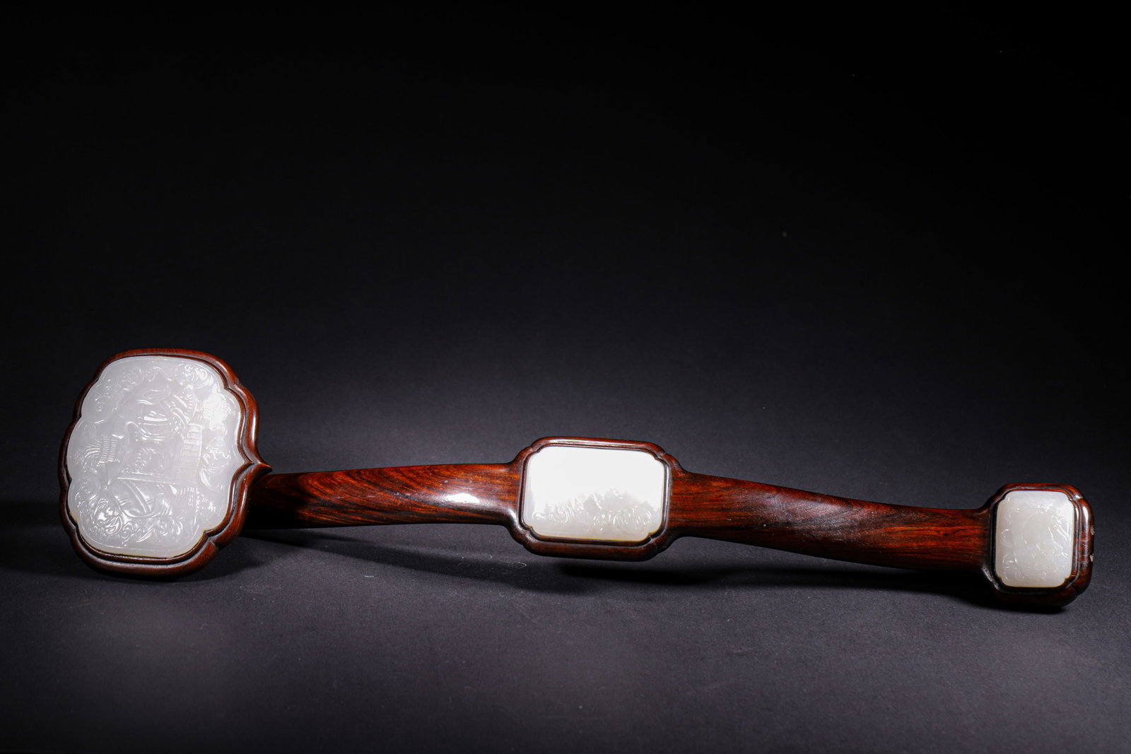 HONGMU RUYI SCEPTRE INLAID WITH THREE HETIAN WHITE JADE PANELS WITH AUSPICIOUS MOTIFS, QING DYNASTY: L 48cm (18.898 in); W 11cm (4.33 in); Wt 438g (0.97 lb),Carved from solid hongmu wood with distinct grain and mellow patina. Three Hetian white jade plaques are inlaid along the shaft. The terminal pl