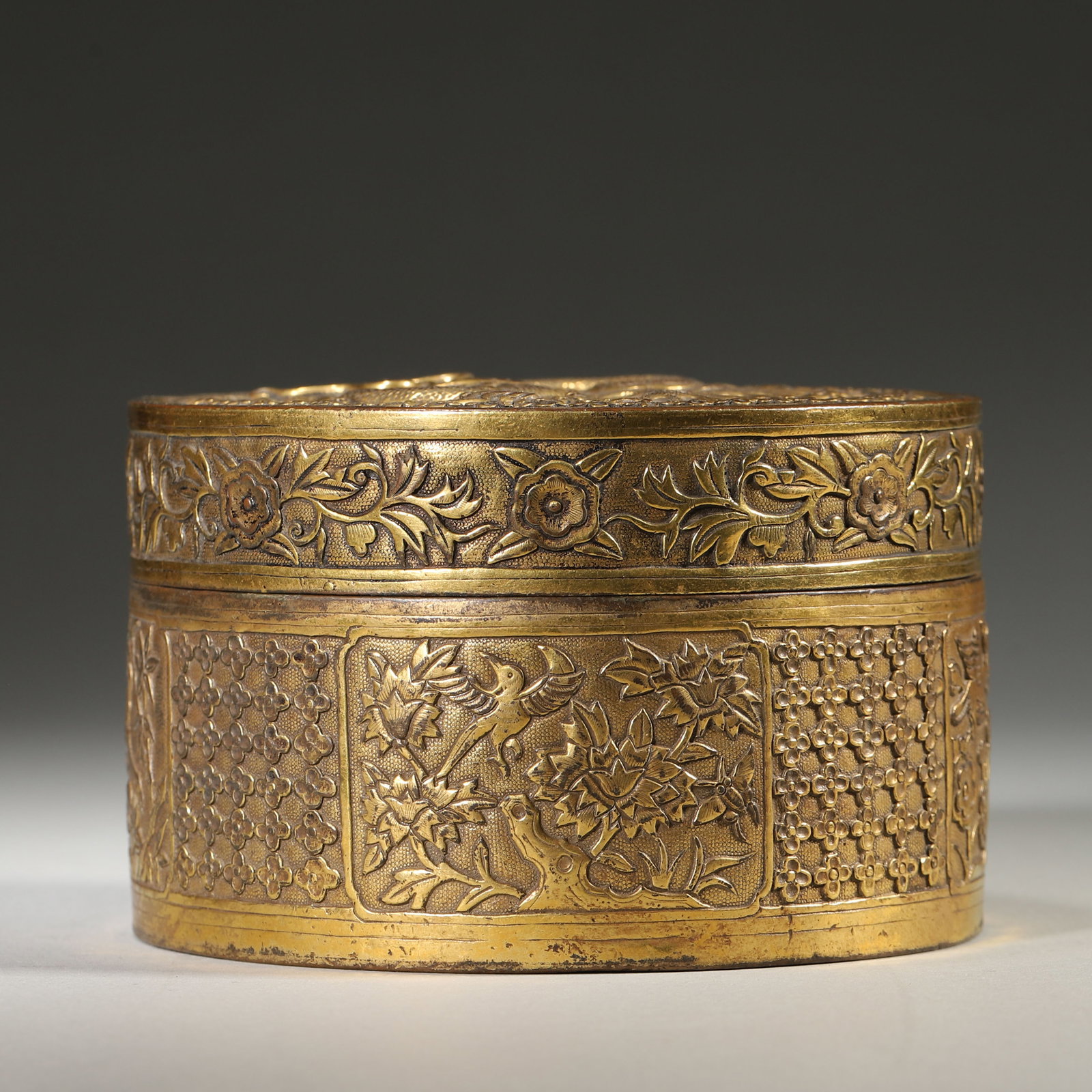GILT BRONZE CIRCULAR BOX WITH DRAGON, FLOWER AND BIRD DECORATION, MARKED DA QING QIAN LONG NIAN ZHI,: Wt 1140g (2.51 lb); D 12.2cm (4.803 in); H 7.5cm (2.95 in),Gilt bronze circular lidded box with fitted rim, fully gilded inside. Cover deeply carved with dragon amid clouds framed by plum blossoms. Bo