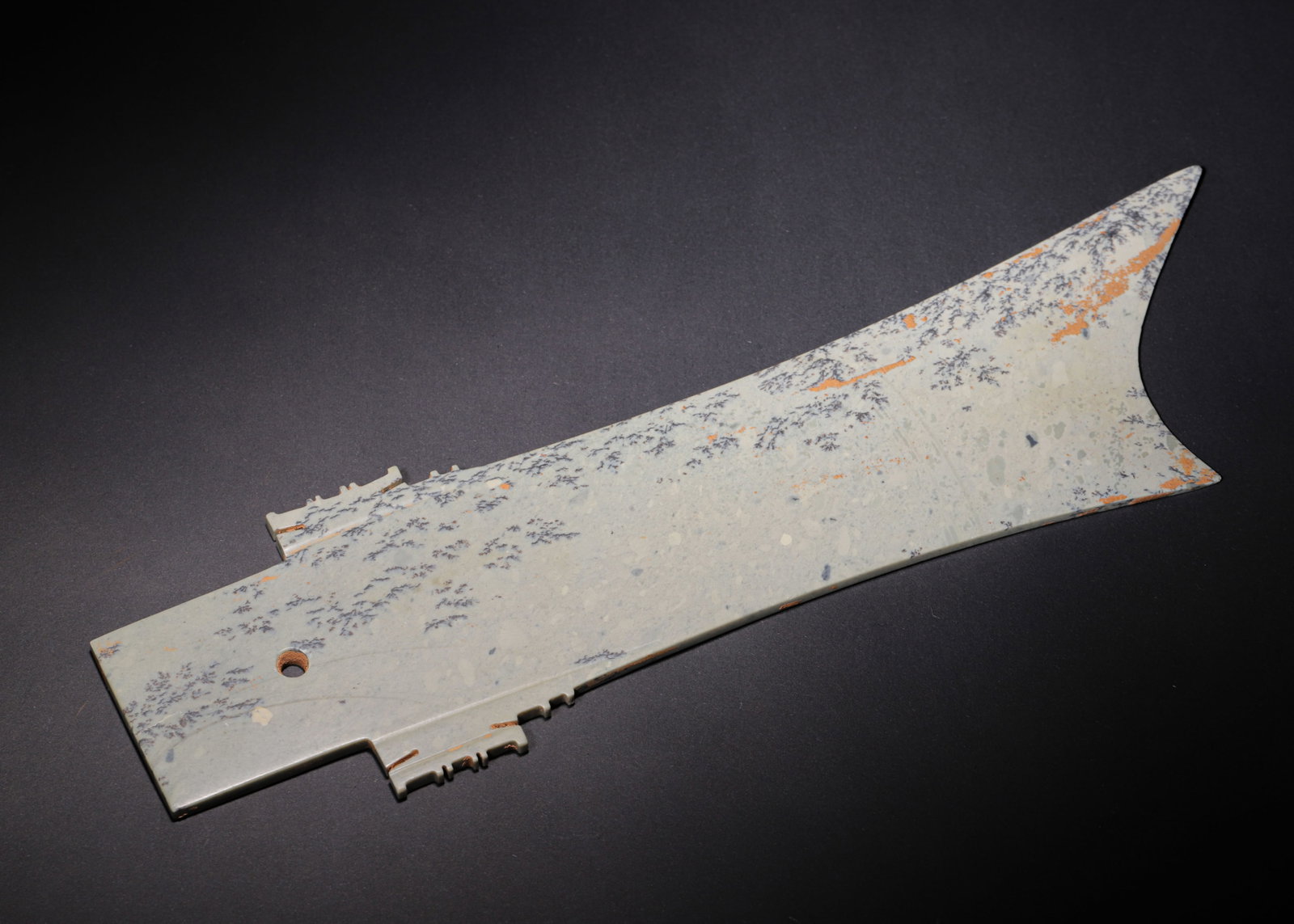 ARCHAIC JADE ZHANG BLADE, SHANG DYNASTY (C.1600?C1046 BC): L 34cm (13.39 in); W 9cm (3.54 in); Wt 393g (0.87 lb),Carved from green jade naturally mottled with dendritic inclusions and russet burial stains. Elongated flat form tapering to a sharp blade tip. Sy