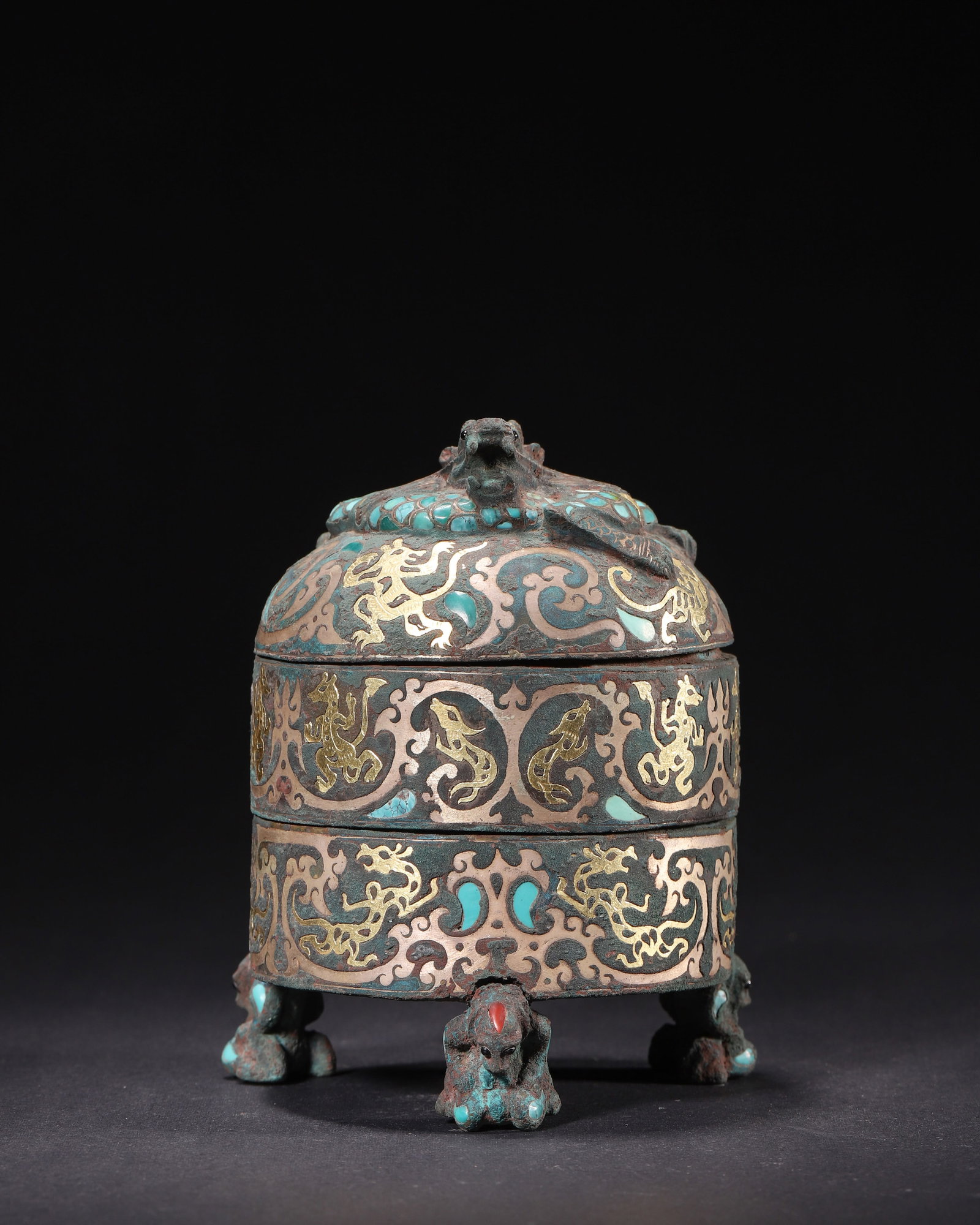 BRONZE THREE-TIERED COSMETIC CASKET INLAID WITH GOLD, SILVER AND TURQUOISE, HAN DYNASTY (202 BC?C220: H 13cm (5.12 in); D 10cm (3.94 in); Wt 871g (1.92 lb),Cast bronze three-section cosmetic casket. Domed lid surmounted by a relief coiled chilong finial inlaid with turquoise. The vessel richly decorat