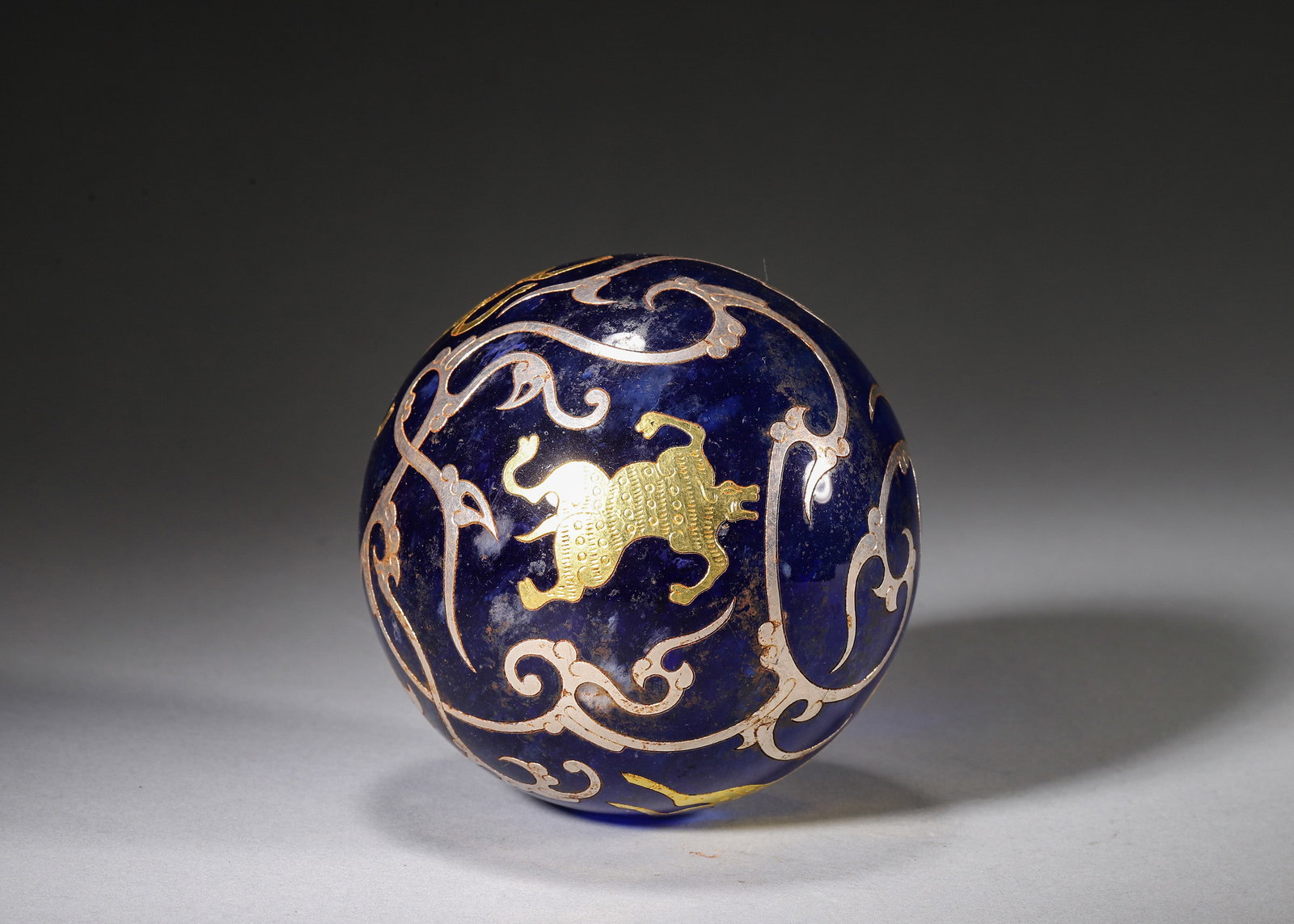 GOLD & SILVER INLAID BLUE GLASS SPHERE WITH FOUR AUSPICIOUS MYTHICAL BEASTS AND CLOUD SCROLLS, HAN