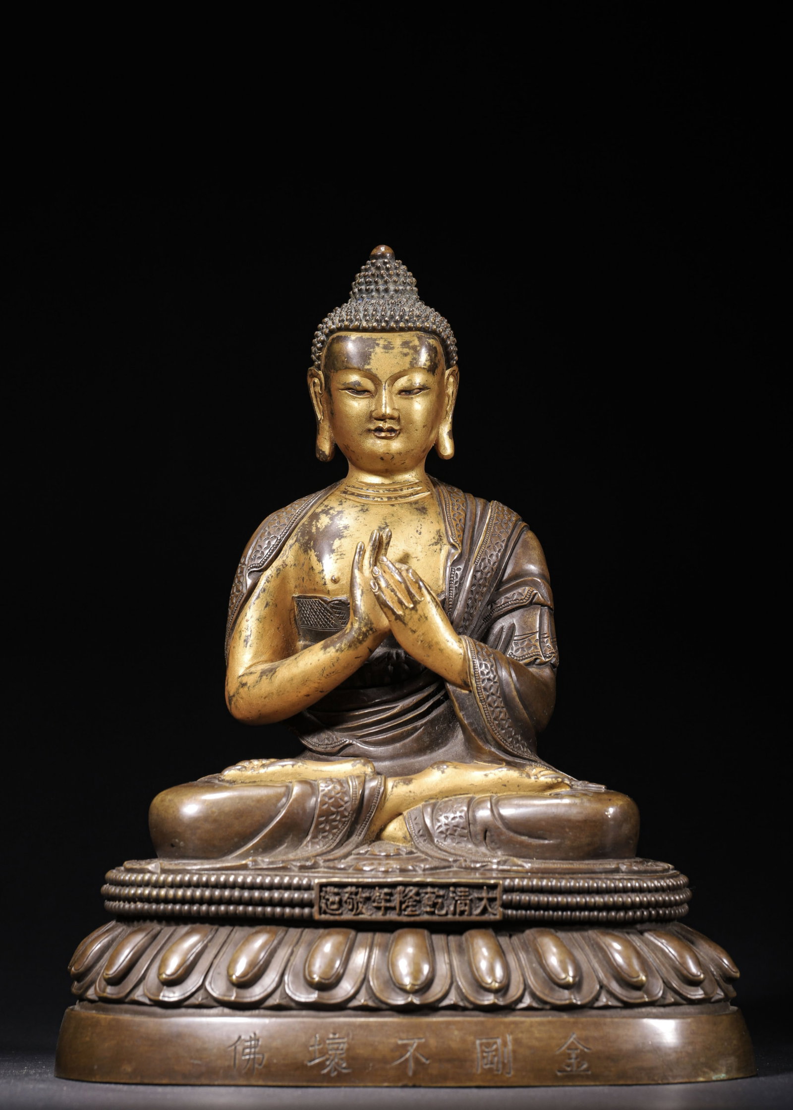 PARTLY GILT COPPER VAJRA AKSHOBHYA BUDDHA, QIANLONG PERIOD, QING DYNASTY (1736-1795 AD): L 20cm (7.87 in); W 14cm (5.51 in); H 25cm (9.84 in); Wt 3891g (8.58 lb),Cast copper with partial gilding on torso and limbs. The Buddha displays ushnisha and serene facial features, seated in full lo