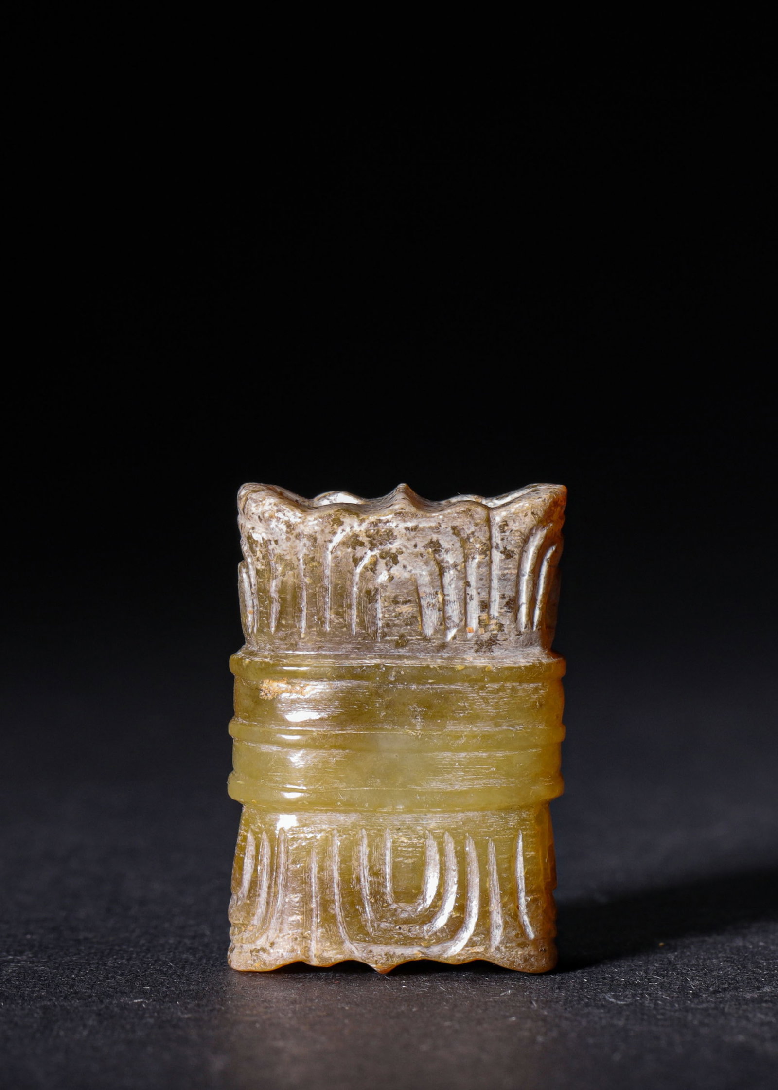 YELLOW JADE DOUBLE-PERFORATED PENDANT WITH RIBBON MOTIFS, HAN DYNASTY (202 BC-220 AD): L 3cm (1.18 in),Carved from yellow jade with extensive pale calcified patina. Flattened rectangular form decorated with ribbon motifs at top and bottom, divided by two raised horizontal ribs. Double p