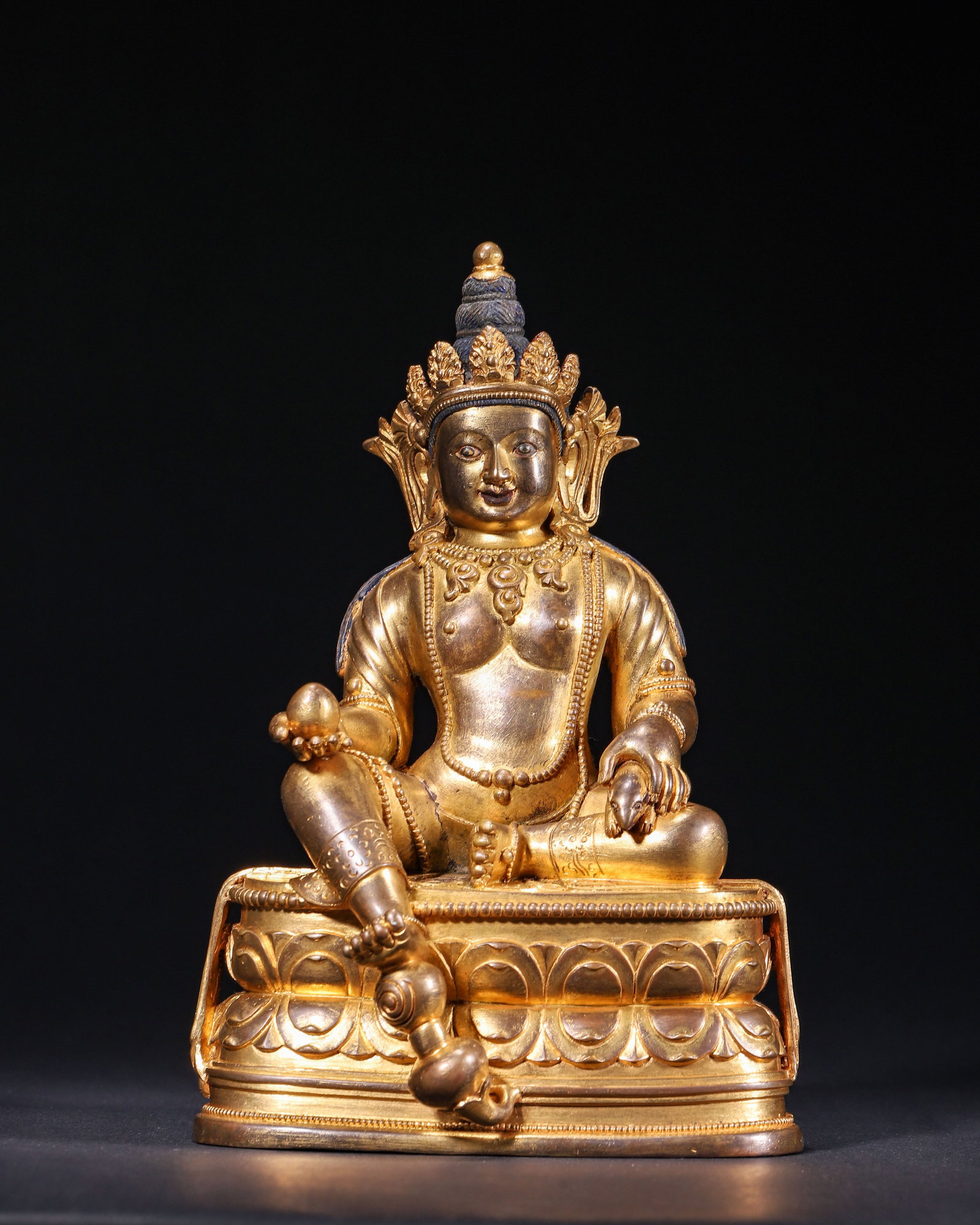 GILT BRONZE JAMBHALA SEATED FIGURE, QING DYNASTY (1644-1912 AD): L 12.00cm (4.72 in); W 9.00cm (3.54 in); H 19.00cm (7.48 in); Wt 1795.00g (3.96 lb),Cast copper fully gilded with warm aged patina. Five-leaf crown sits atop hair retaining traces of blue pigment, plu