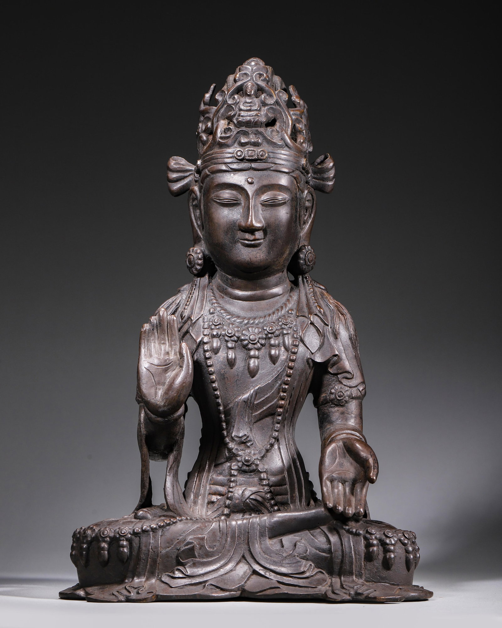 BRONZE SEATED GUANYIN BODHISATTVA, LIAO DYNASTY, 907?C1125 AD: L 23.00cm (9.06 in); W 19.00cm (7.48 in); H 36.00cm (14.17 in); Wt 6453.00g (14.23 lb),Guanyin Bodhisattva seated in padmasana, wearing an openwork crown inset with a small Buddha. The rounded face be