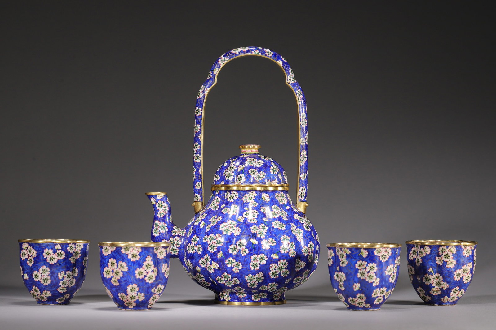 SET OF COPPER-BODY PAINTED ENAMEL TEA WARES: ONE LIDDED HANDLE TEAPOT & FOUR CUPS WITH PLUM BLOSSOM: Pot L 13cm (5.12 in); W 10cm (3.94 in); H 20cm (7.87 in); Total Wt 842g (1.86 lb),Suite including one melon-ribbed handled teapot and four flower-rimmed cups, copper body with gilt rims. Decorated wit