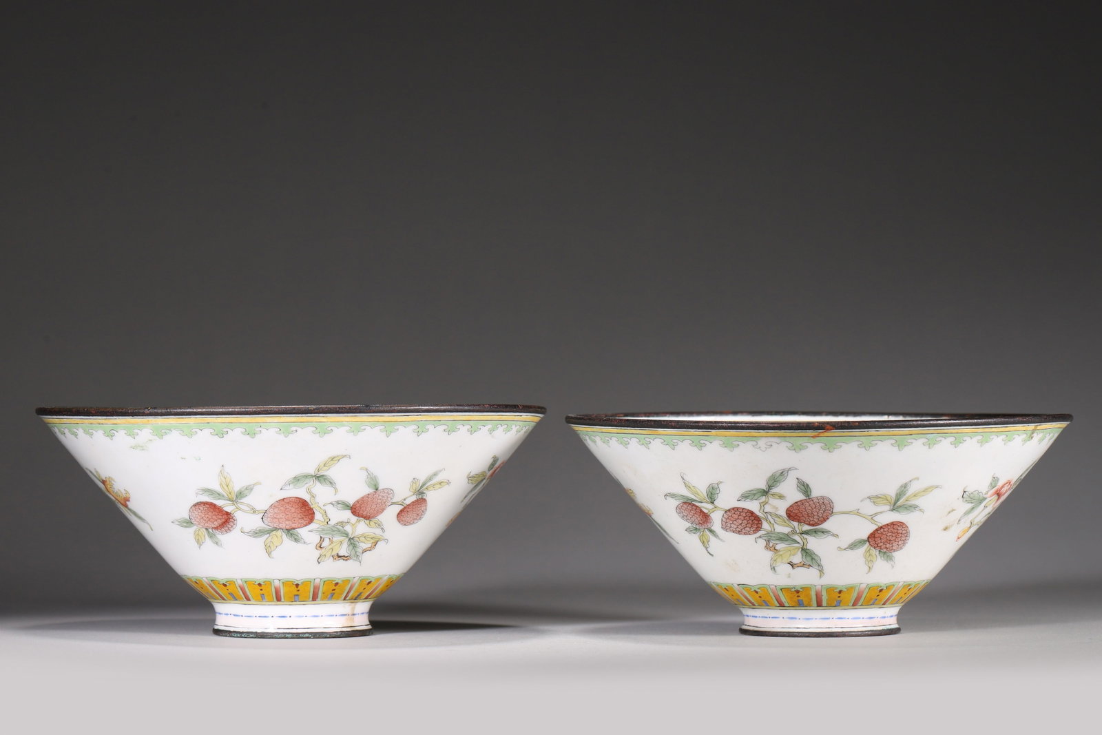PAIR OF COPPER-BODY PAINTED ENAMEL CONICAL BOWLS WITH THREE ABUNDANCES MOTIF, QIANLONG PERIOD, QING: D 15.5cm (6.10 in); H 7cm (2.76 in); Wt 618g (1.36 lb),Copper body with copper bound rim. Exterior painted with pomegranates, peaches and citrons on white ground, bordered by scrollwork and geometric 