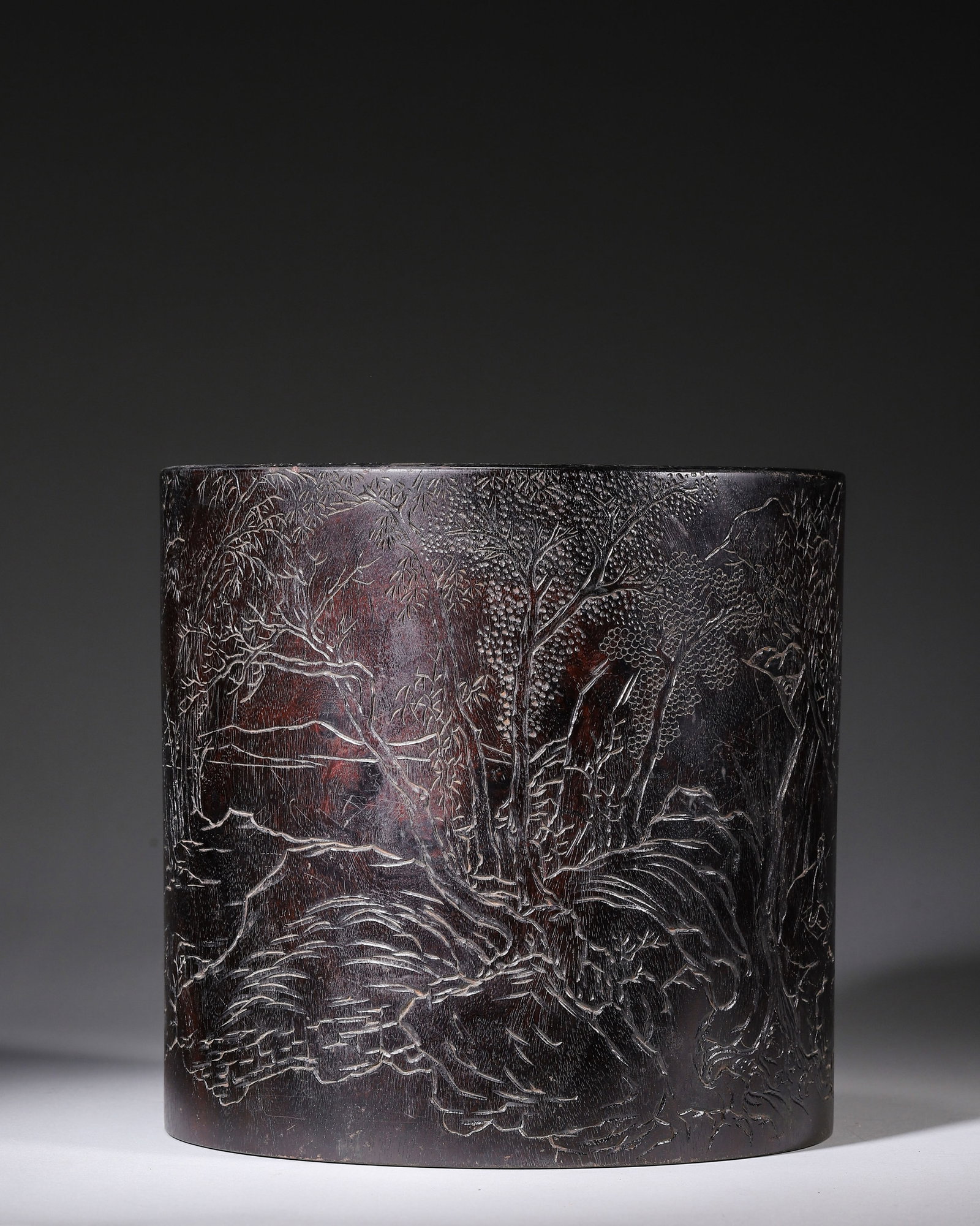 QING DYNASTY ZITAN BRUSH POT FINELY INCISED WITH "CARRYING ZITHER TO VIEW WATERFALL" LANDSCAPE,: H 19.00cm (7.48 in); D 20.00cm (7.87 in); Wt 2122.00g (4.68 lb),Hollowed from a single solid zitan log with dense ox-hair grain and age patina scratches. The barrel fully incised with a scene of a sch