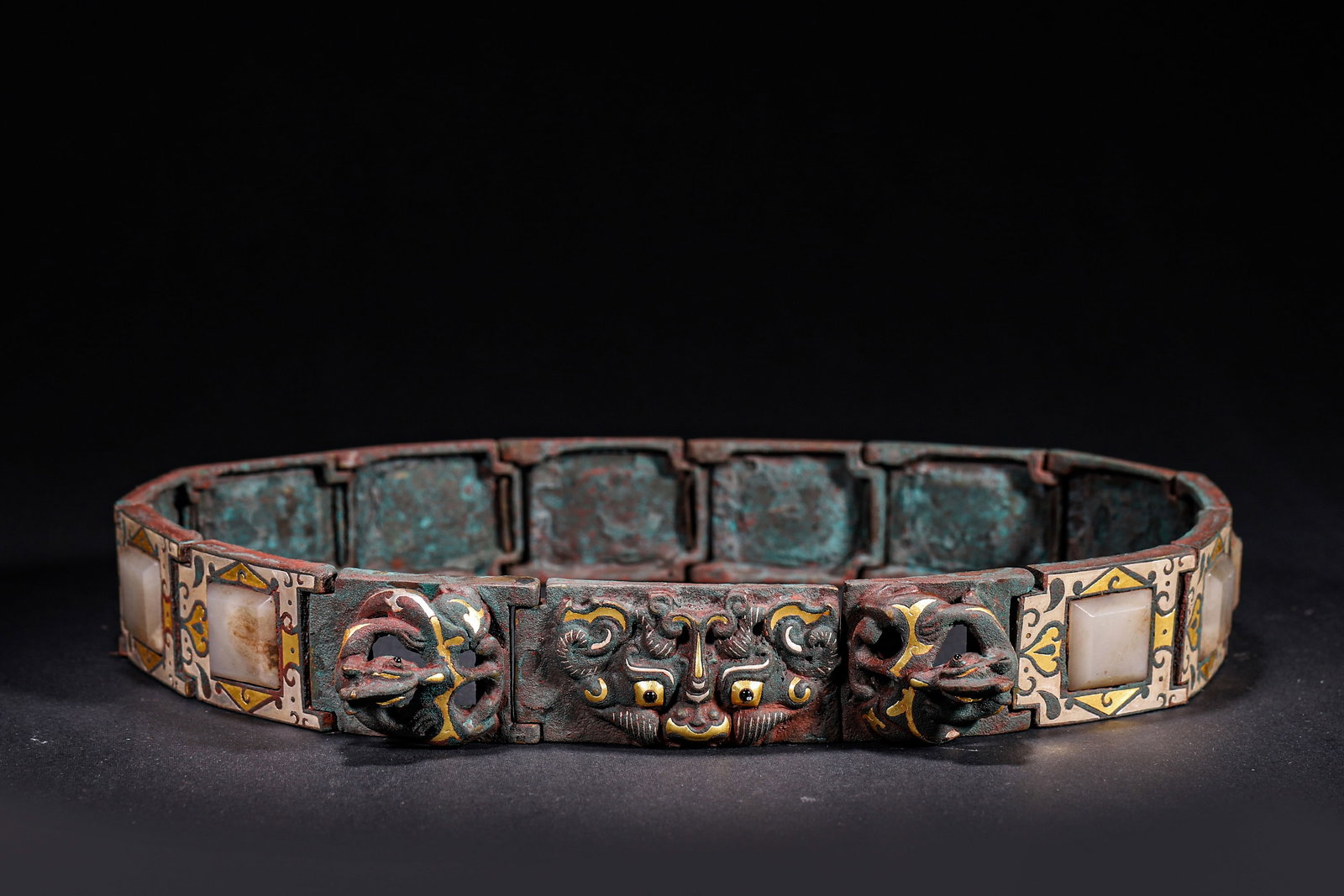 ARTICULATED BRONZE BELT WITH GOLD & SILVER INLAY AND JADE INLAYS, BEAST MASK AND CHILONG MOTIFS, HAN: L 77cm (30.31 in); W 4cm (1.57 in); Wt 1022g (2.25 lb),Articulated bronze belt constructed with hinged segments. The front centre features a high-relief beast mask flanked by openwork chilong buckles.