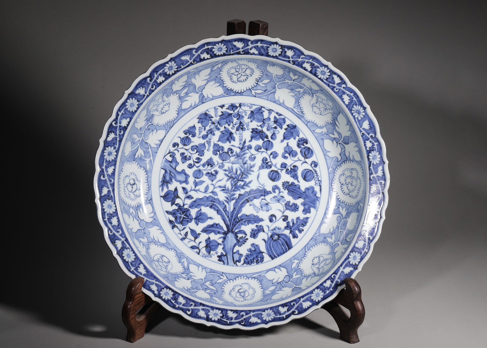 A BLUE AND WHITE FOLIATE-RIM CHARGER WITH FRUIT AND FLORAL MOTIFS, YUAN DYNASTY (1 of 7)