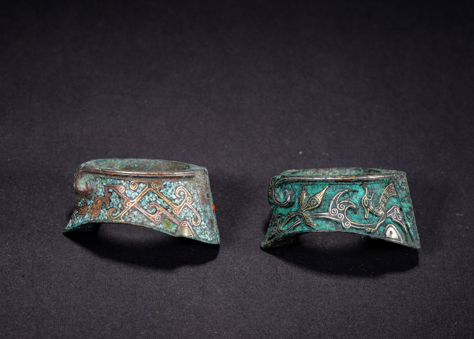 A PAIR OF GOLD, SILVER AND TURQUOISE-INLAID BRONZE CROSSBOW FITTINGS, EASTERN ZHOU DYNASTY (770-221: L 4.3cm (1.69 in); W 3.2cm (1.26 in); H 2.2cm (0.87 in); Wt 76g (0.17 lb),Cast bronze, offered as a matched pair. One inlaid with crushed turquoise alongside gold and silver geometric scroll patterns;
